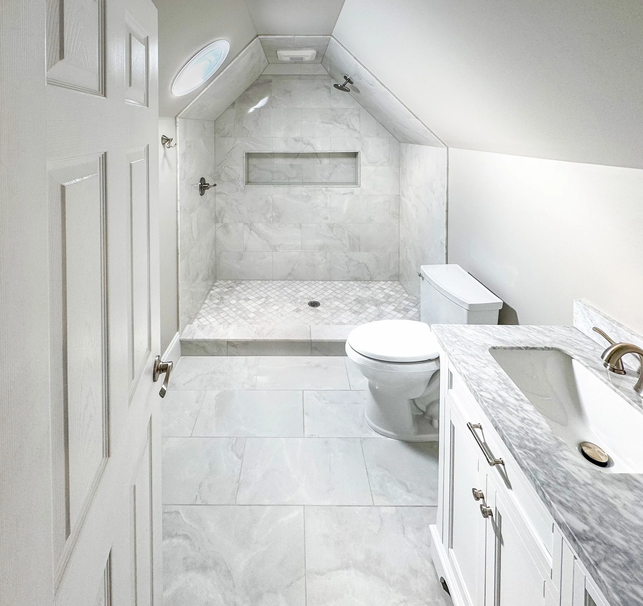 Finished attic bathroom remodel with walk-in tile shower, marble vanity, and sloped ceiling design in Fuquay-Varina NC
