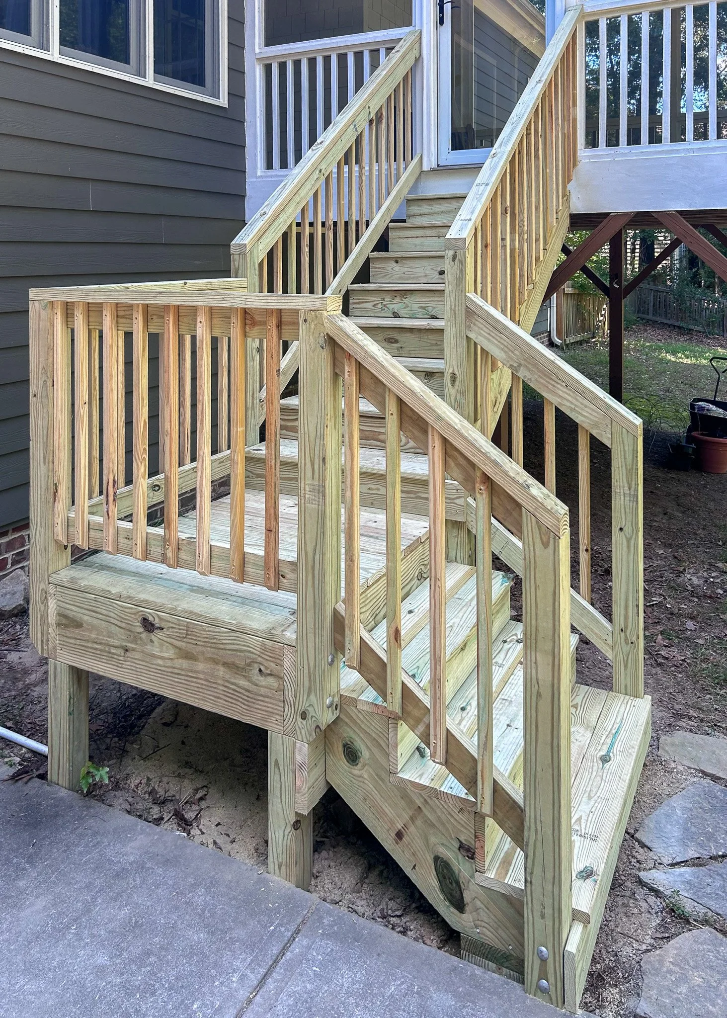 Newly built wooden staircase with railings leading to a house porch.