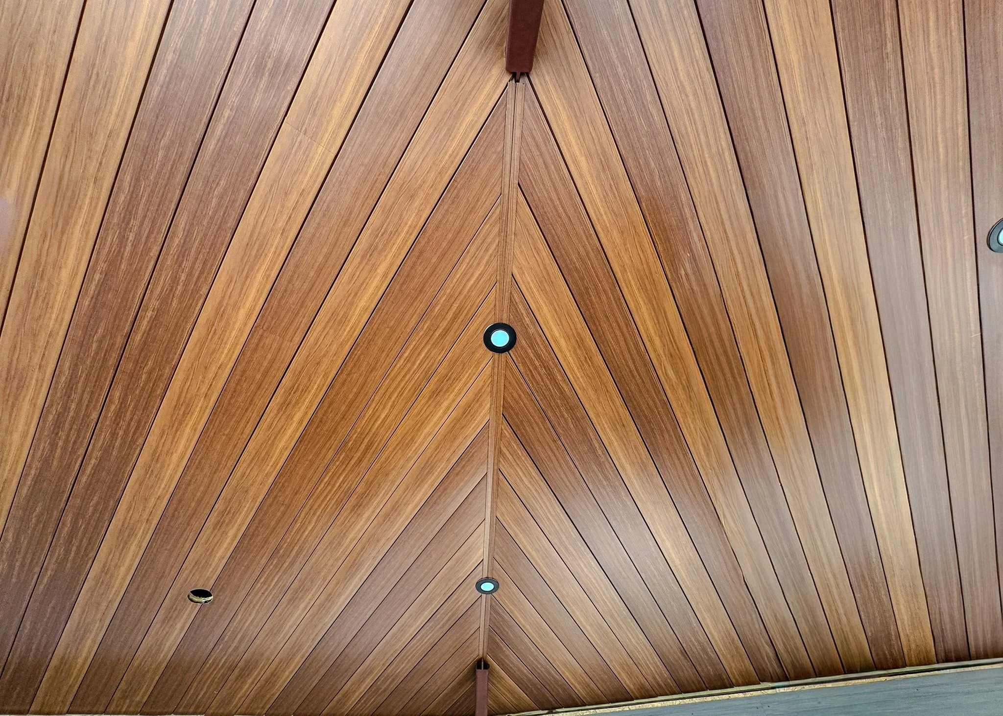 Wooden ceiling with recessed lights and a red ladder in the foreground.