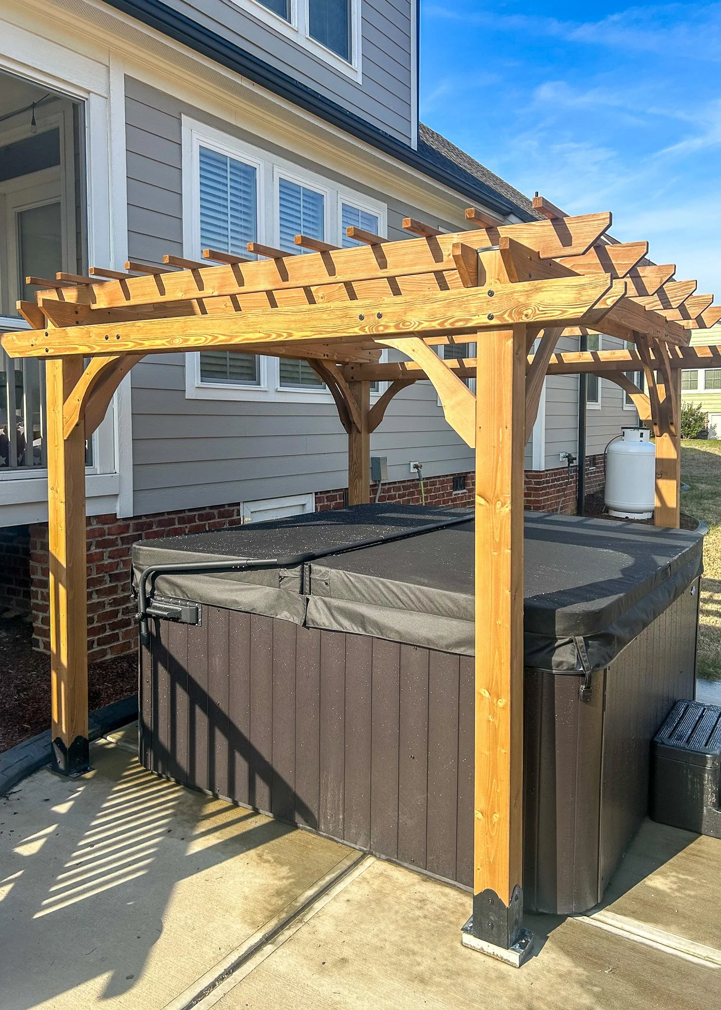 Wooden pergola frame over hot tub outside house