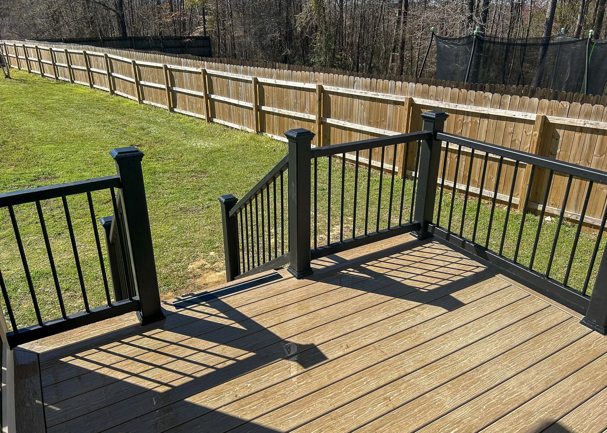 Composite deck with black metal railings overlooking grassy yard.