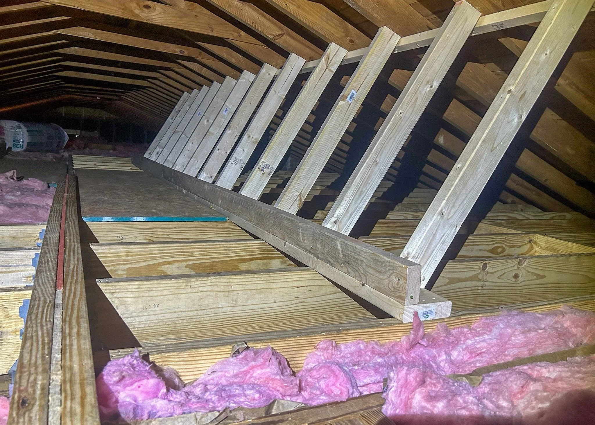 Attic framing with wooden beams and pink insulation in the ceiling