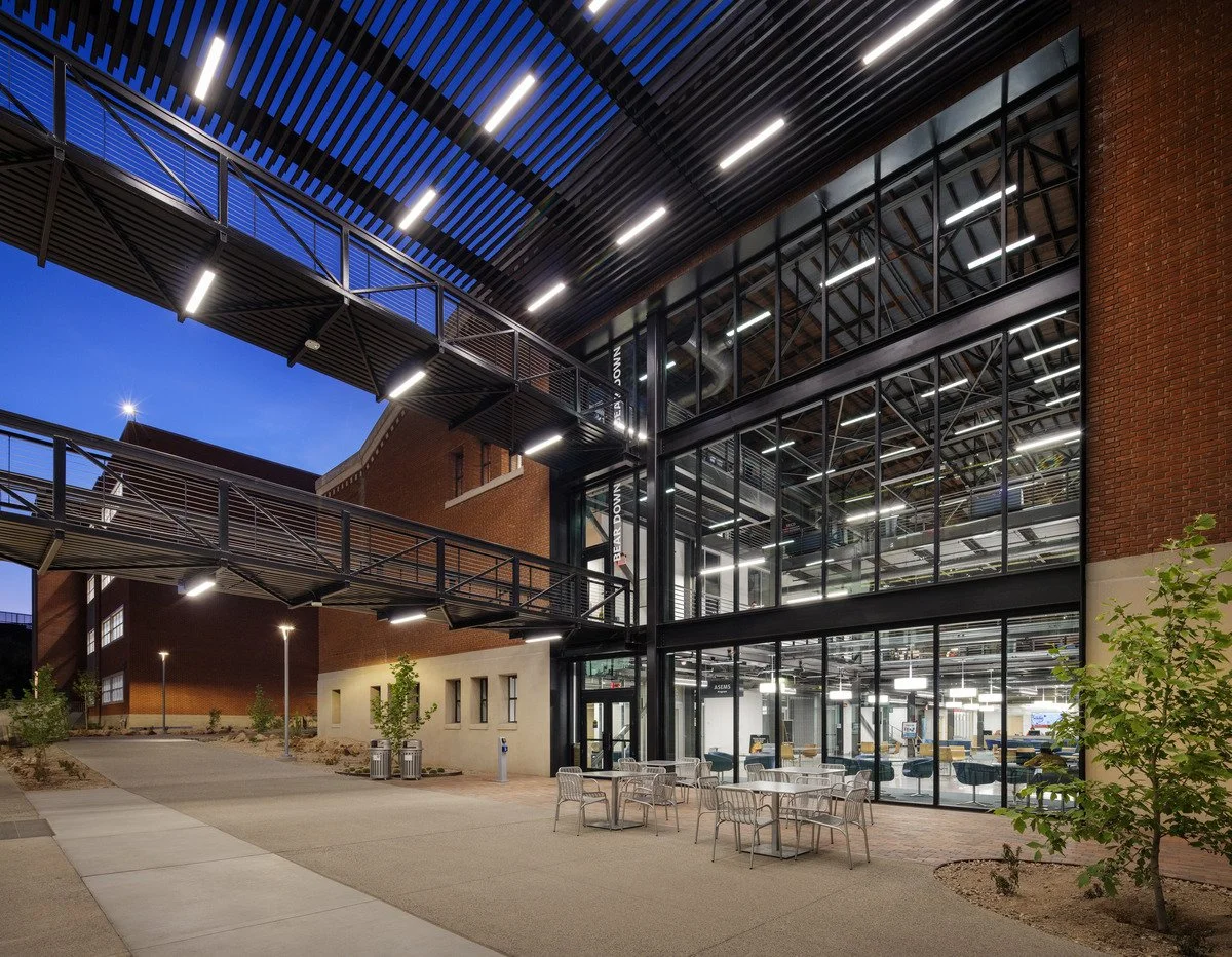 The Student Success Center at dusk is defined by ceiling surface-mounted architectural lighting at the building entrance and interior pendant fixtures 