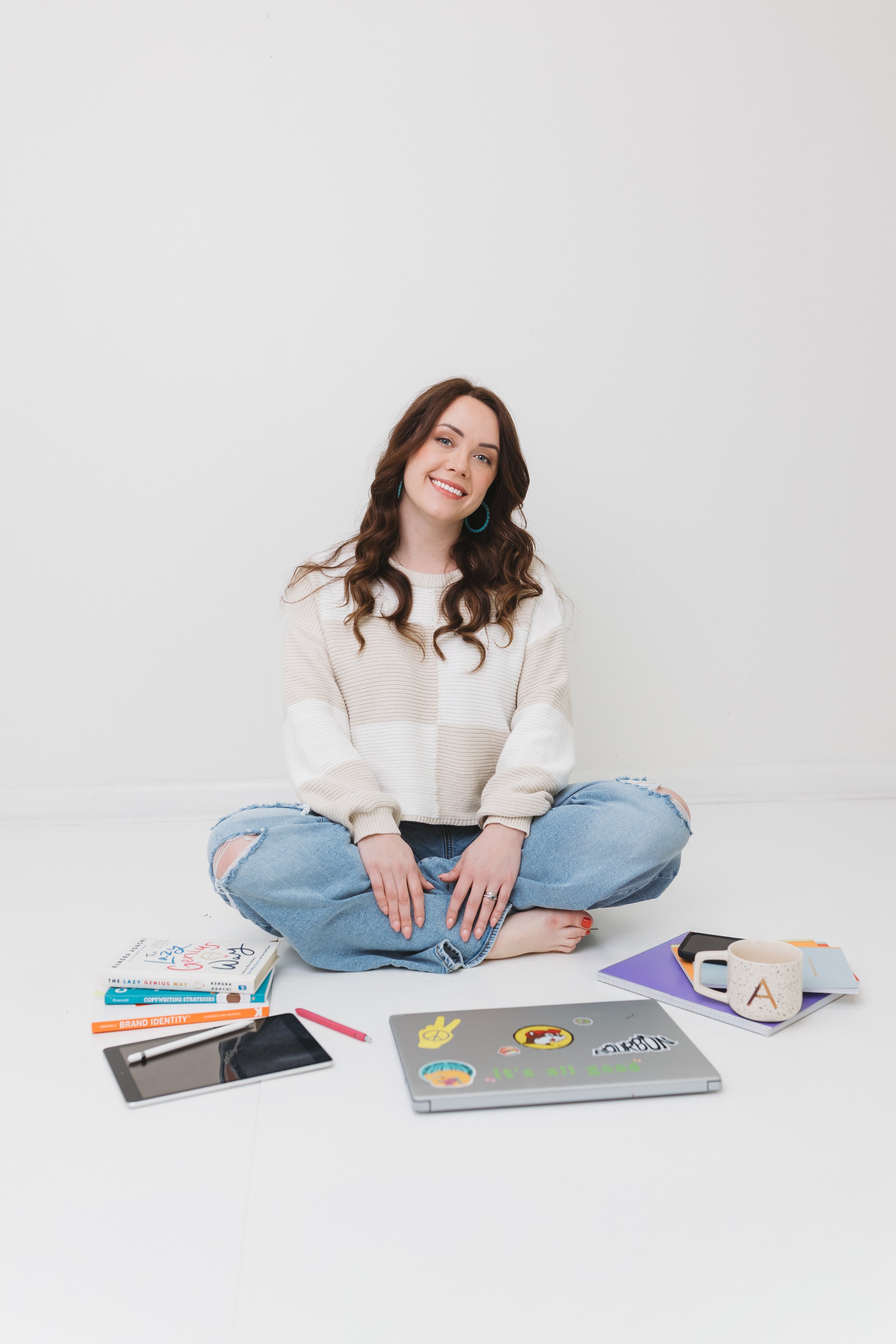 Virtual assistant for photographers amanda the assistant is seated with laptop, books, & ipad in a photo studio.
