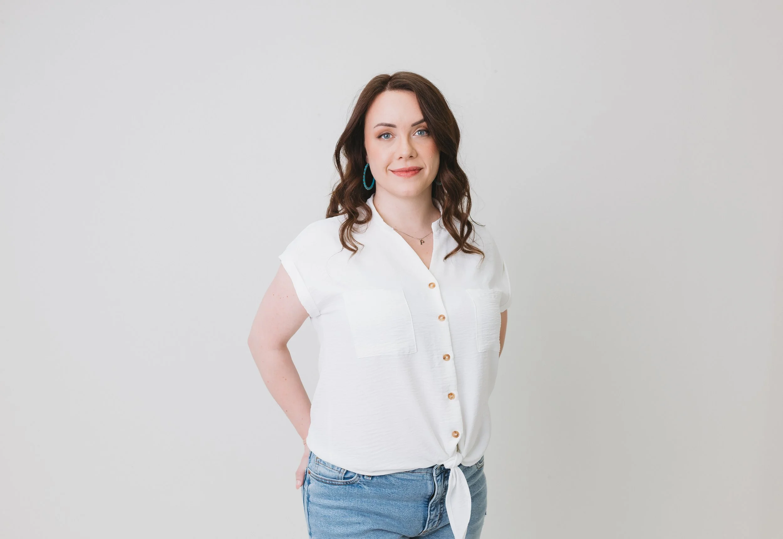 Evergreen marketing provider Amanda the Assistant stands before a white wall wearing a white shirt & jeans.
