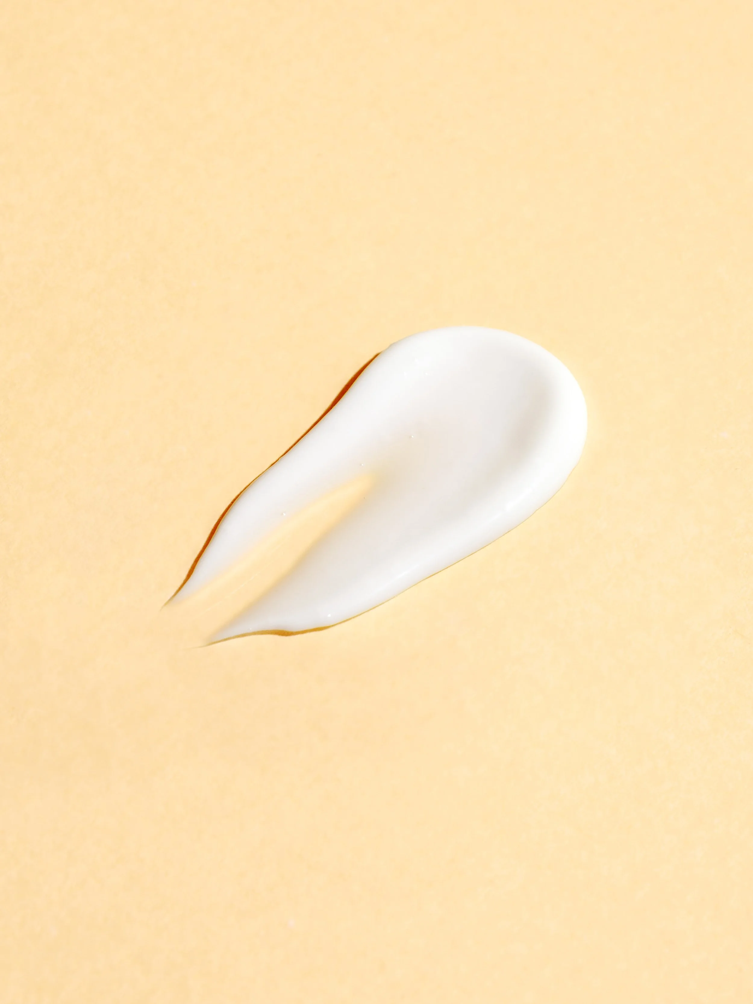 Tache blanche de crème ou de lotion sur un fond jaune clair