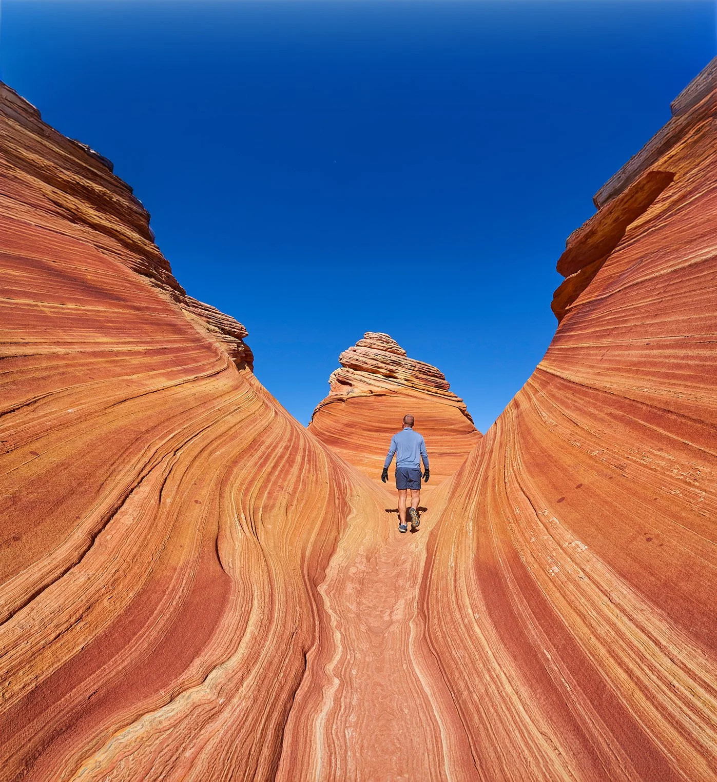 man walking on rock that has been eroded over many years