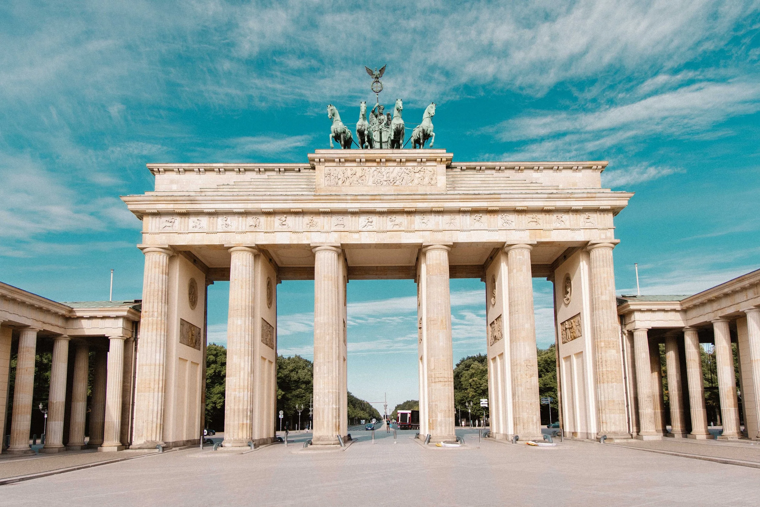 The Brandenburg Gate, a neoclassical monument in Berlin, Germany, with a quadriga sculpture on top, against a blue sky with wispy clouds.