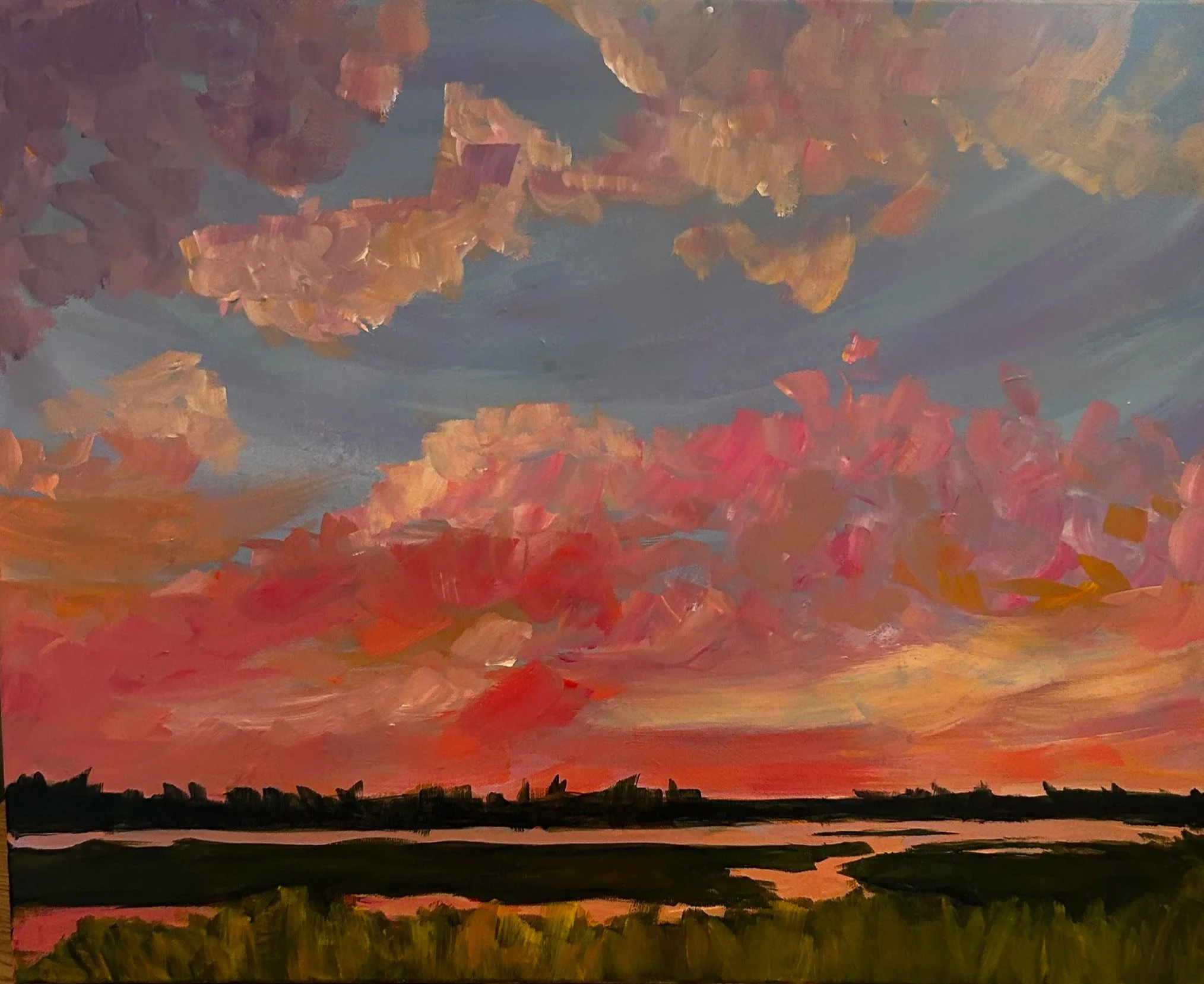 A vibrant sunset with a vivid orange and red sky, silhouetted green landscape, and dark horizon.