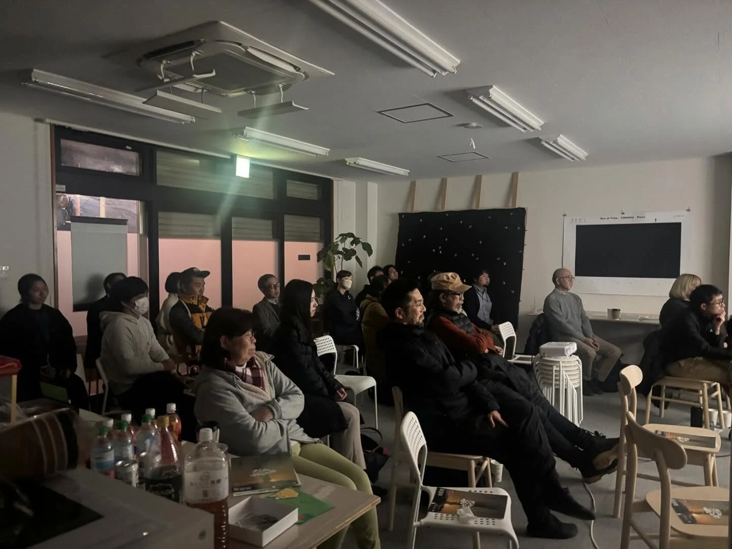 _
＼12月18日月の下アートセンター開催レポート／

2025年12月18日、アートセンターが一夜限りのシアターになりました。
上映したのは、ドキュメンタリー映画『三角屋の交差点で（2025）』。監督の山田徹さんを迎え、20名の来場者のみなさんとともに静かな時間を過ごしました。

この作品は2018年から大熊・浪江にゆかりのあるご家族を追って撮影されてきた作品であり、この日は浜通りで初めての先行上映の機会となりました。
アフタートークでは、監督から制作のきっかけやタイトルに込めた思いが語られ、