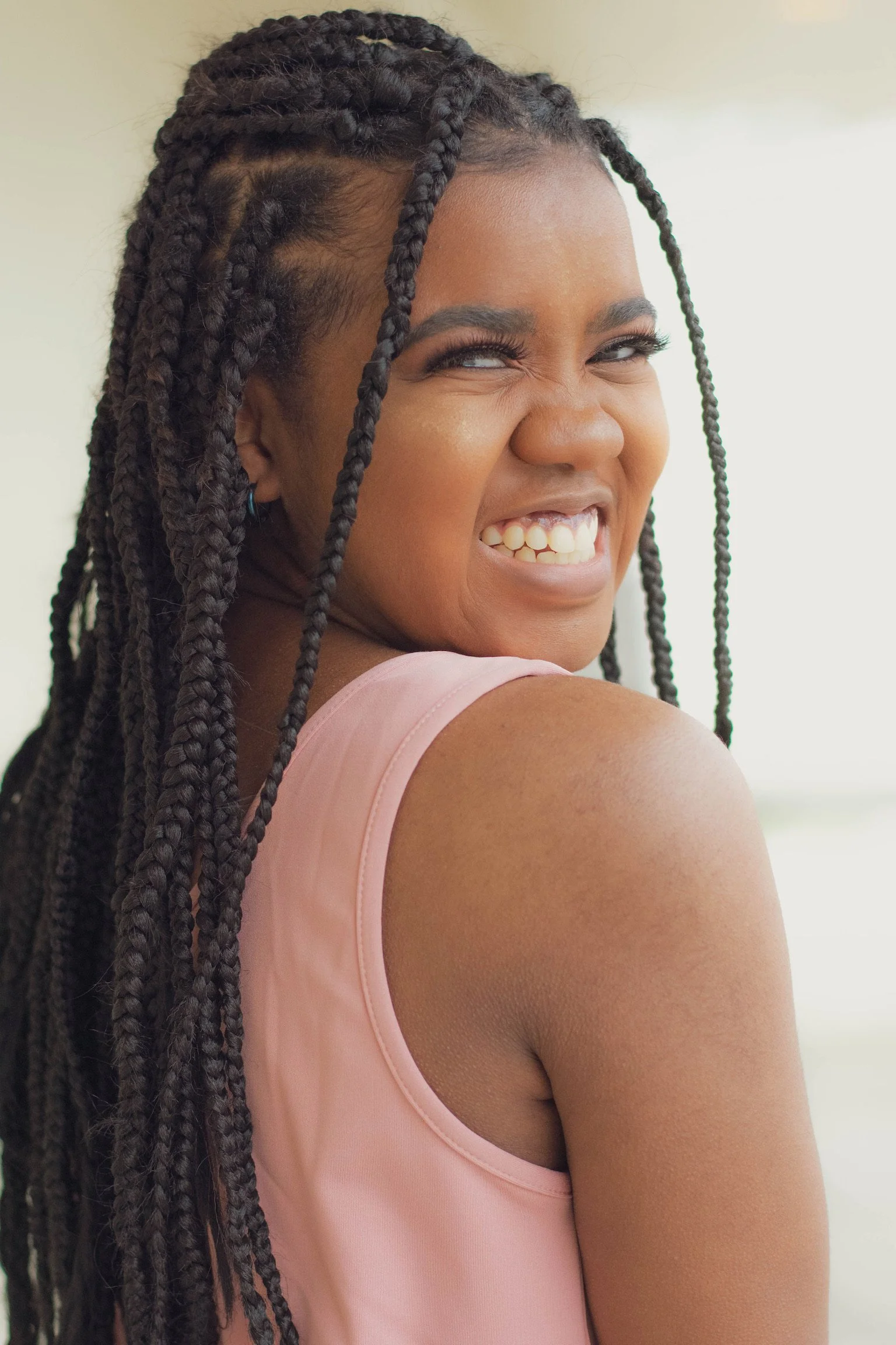 A smiling woman with long braided hair looking over her shoulder.