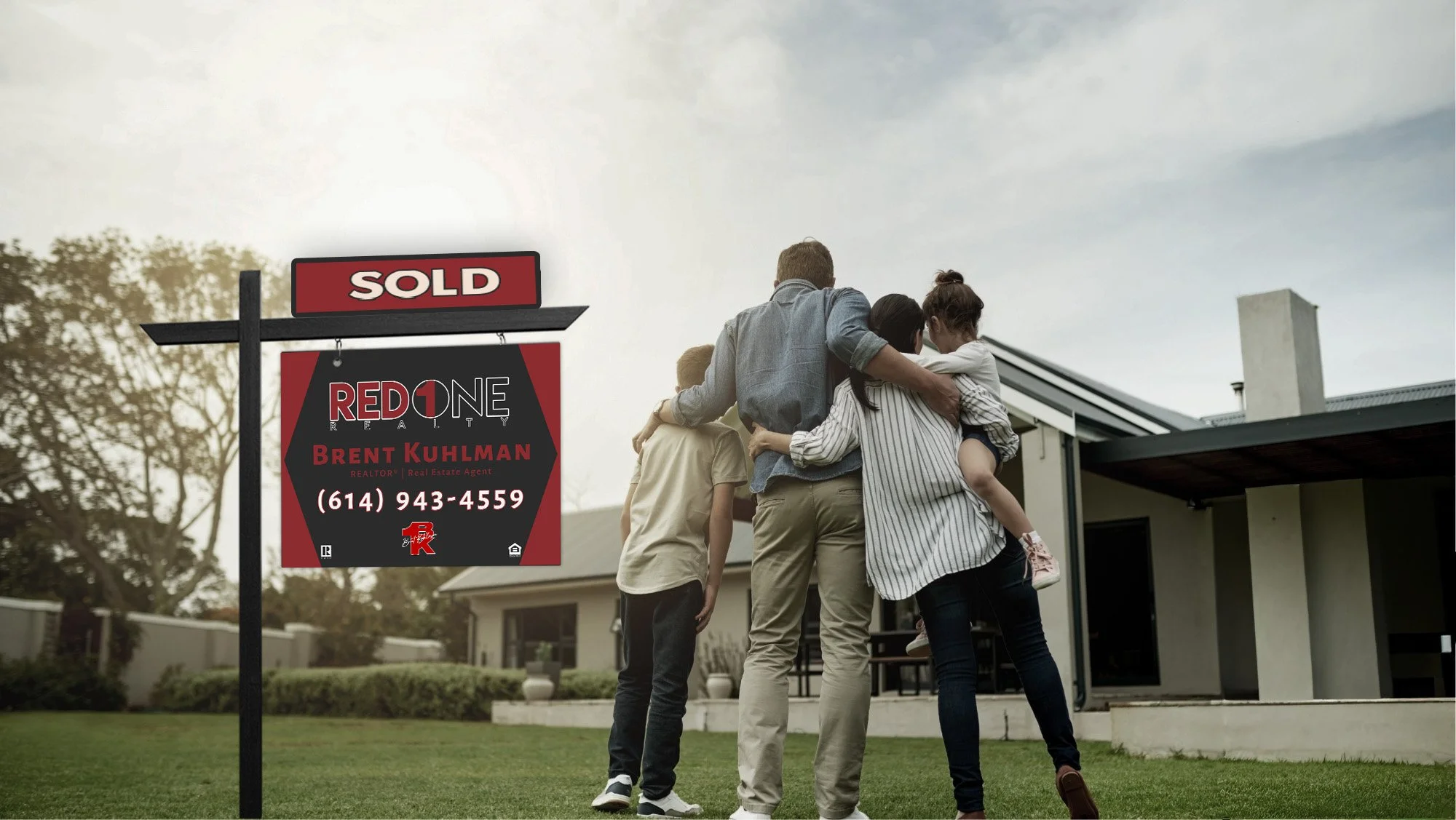family in front of new house with a sold sign in the front yard, symbolizing moving up and upgrading from a starter home