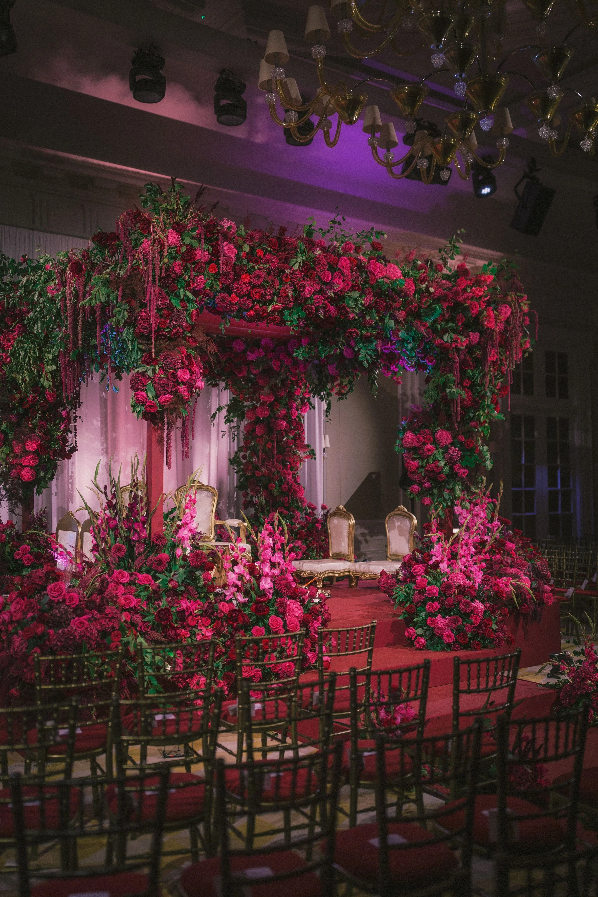 Luxury floral mandap by Amie Bone Flowers at Raffles London, featuring opulent red and pink blooms, lush greenery, and elegant details for a statement wedding ceremony design.