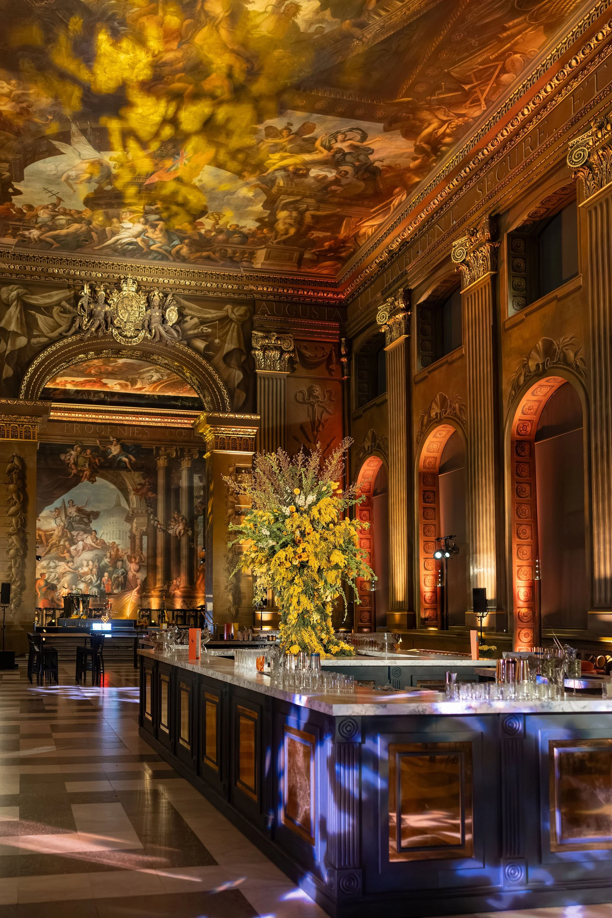 Wide view of the Painted Hall bar styled with statement spring florals and sculptural urn arrangements