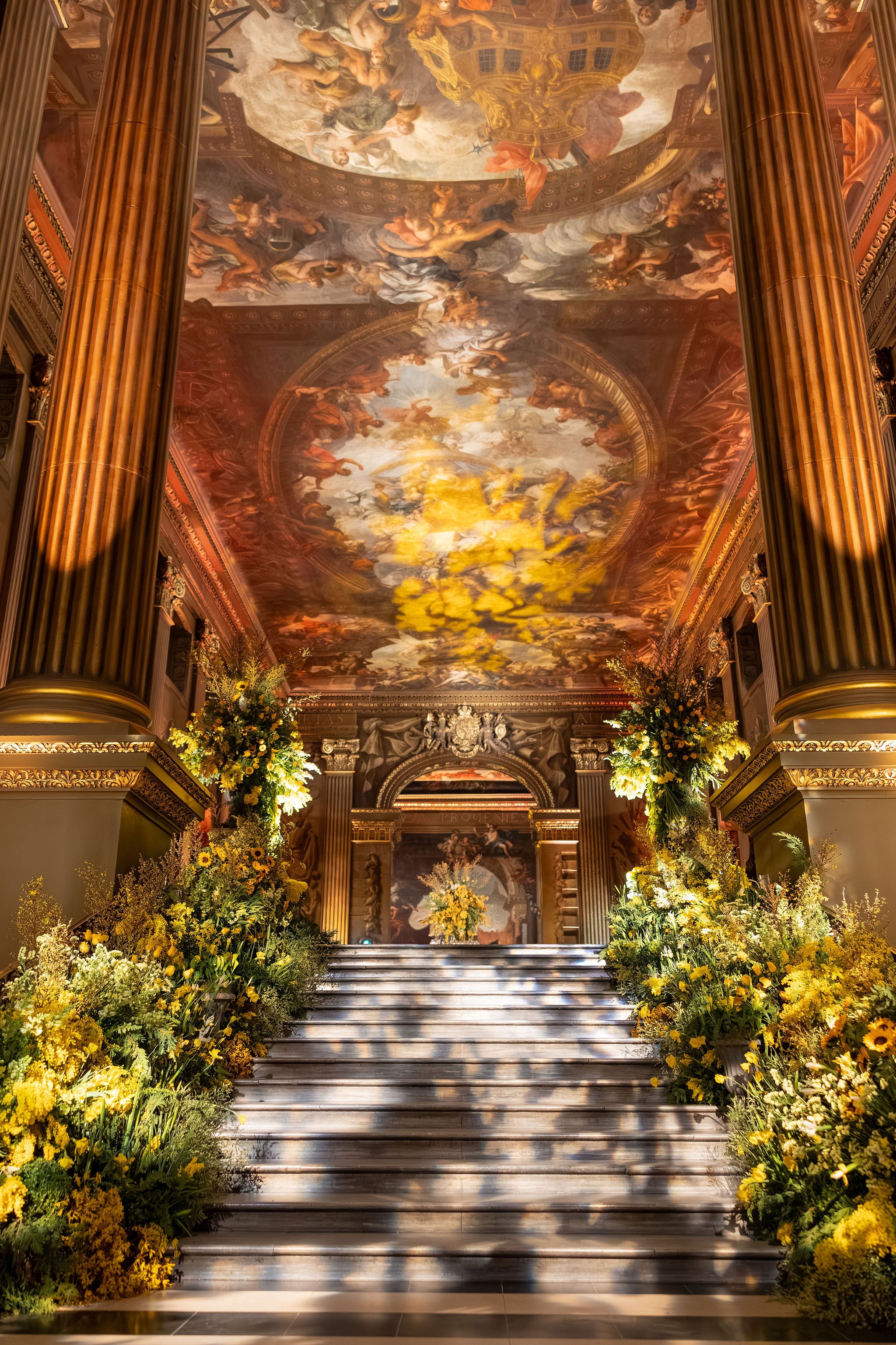 Statement staircase floral installation with cascading yellow mimosa at the Old Royal Naval College in Greenwich
