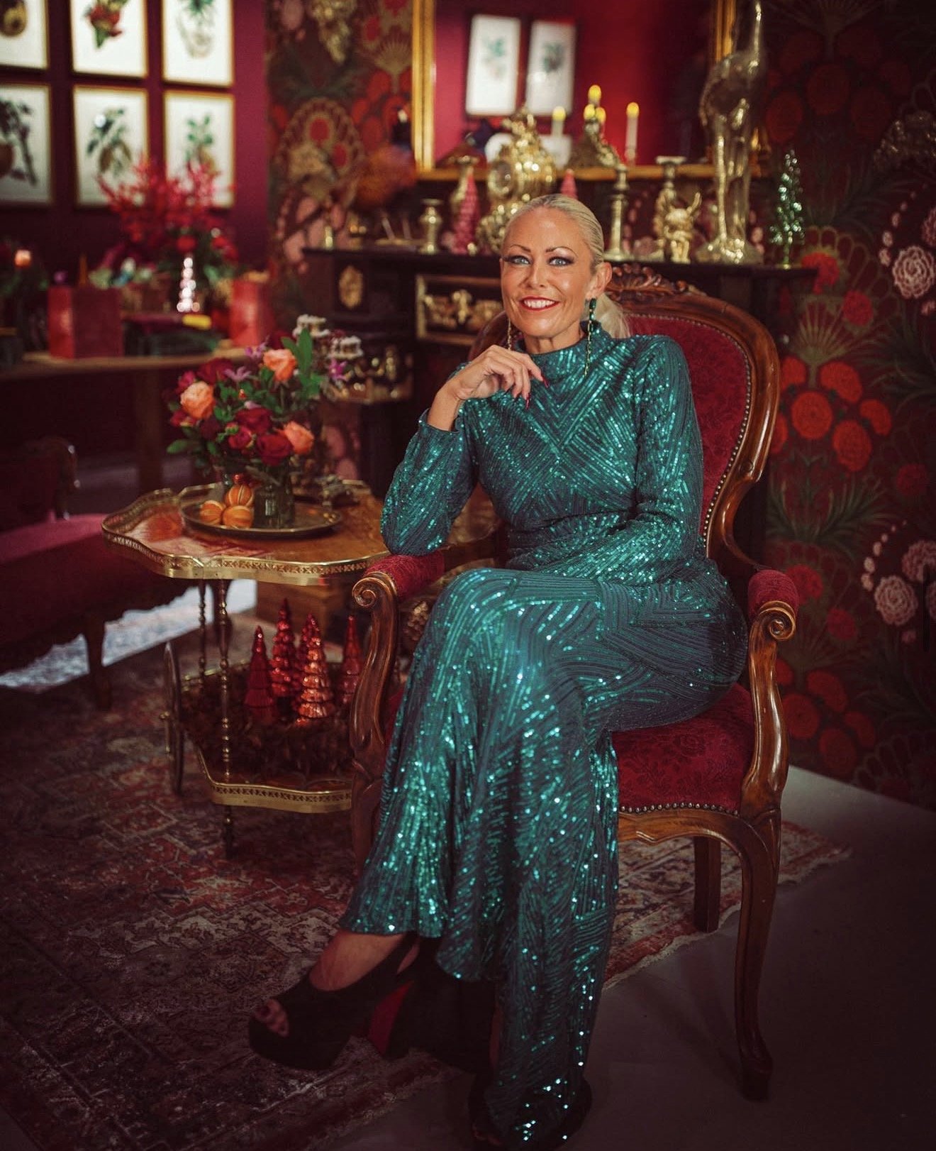 Portrait of luxury floral designer Amie Bone seated in a festive interior, surrounded by rich seasonal décor, vintage furniture and Christmas styling inspiration.