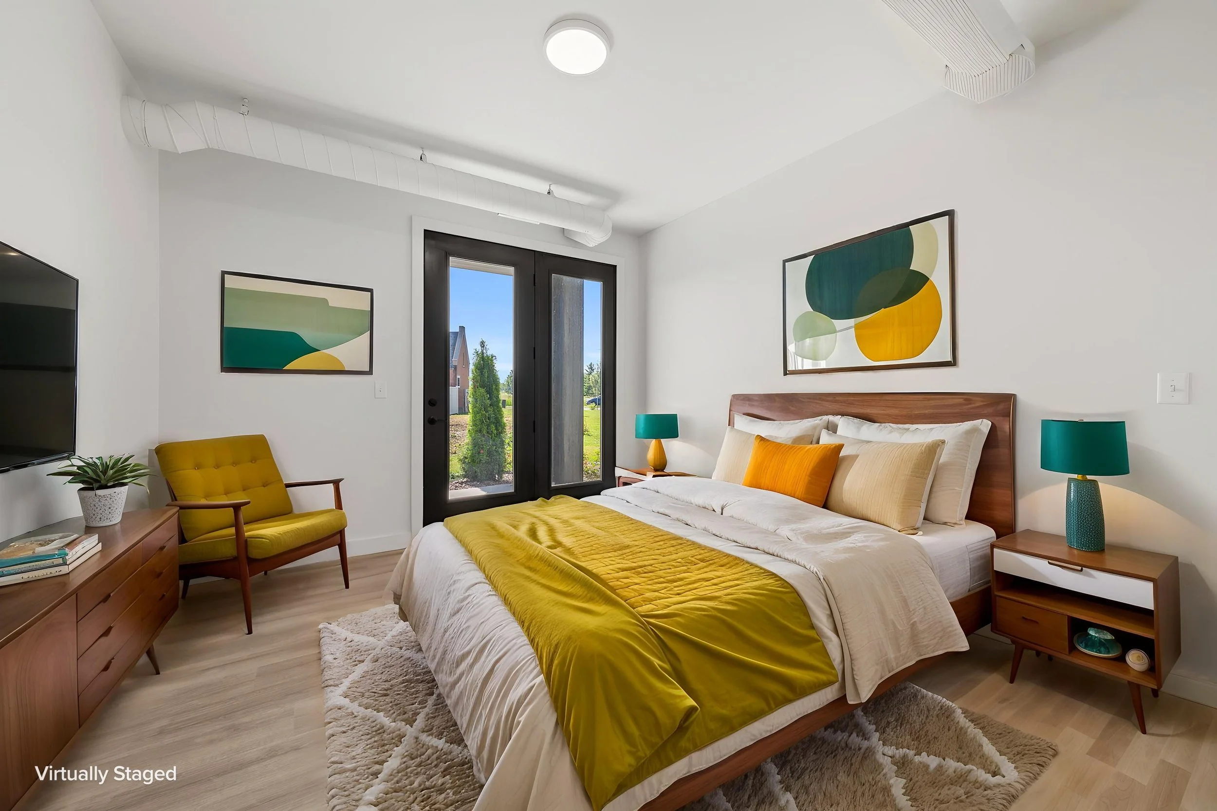 A bedroom with a bed, yellow and white bedding, and matching yellow and blue lamps on white nightstands. The Residences at North Harbor on Lake Superior in Marquette Michigan.