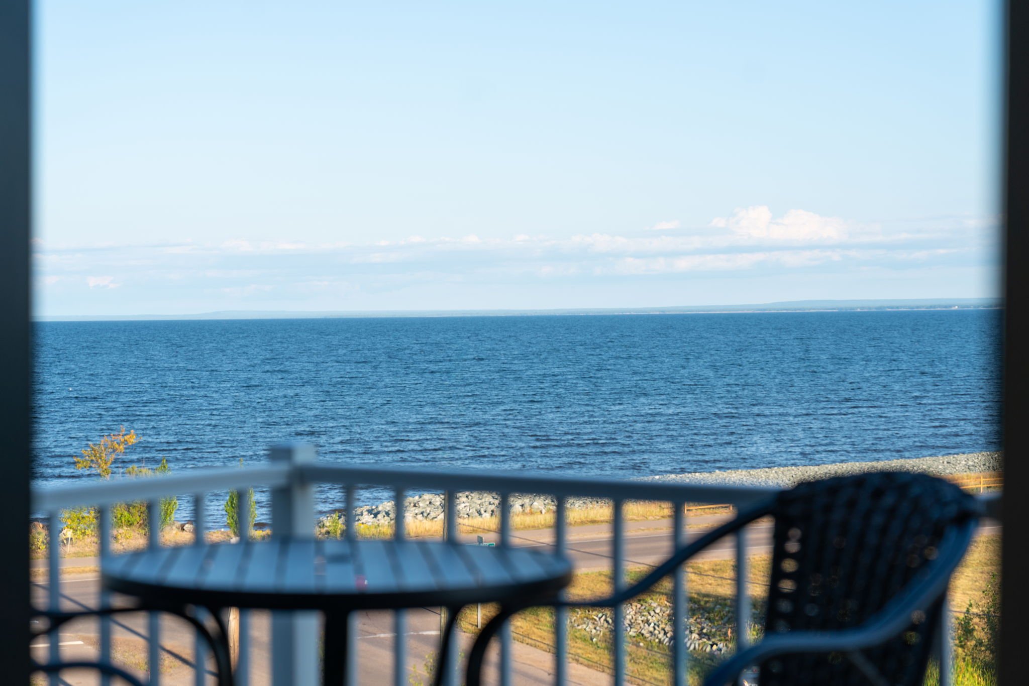 Photo taken from inside a boat showing a view of Lake Superior, the sky with clouds, and a distant shoreline with trees and landforms. The Residences at North Harbor on Lake Superior in Marquette Michigan.