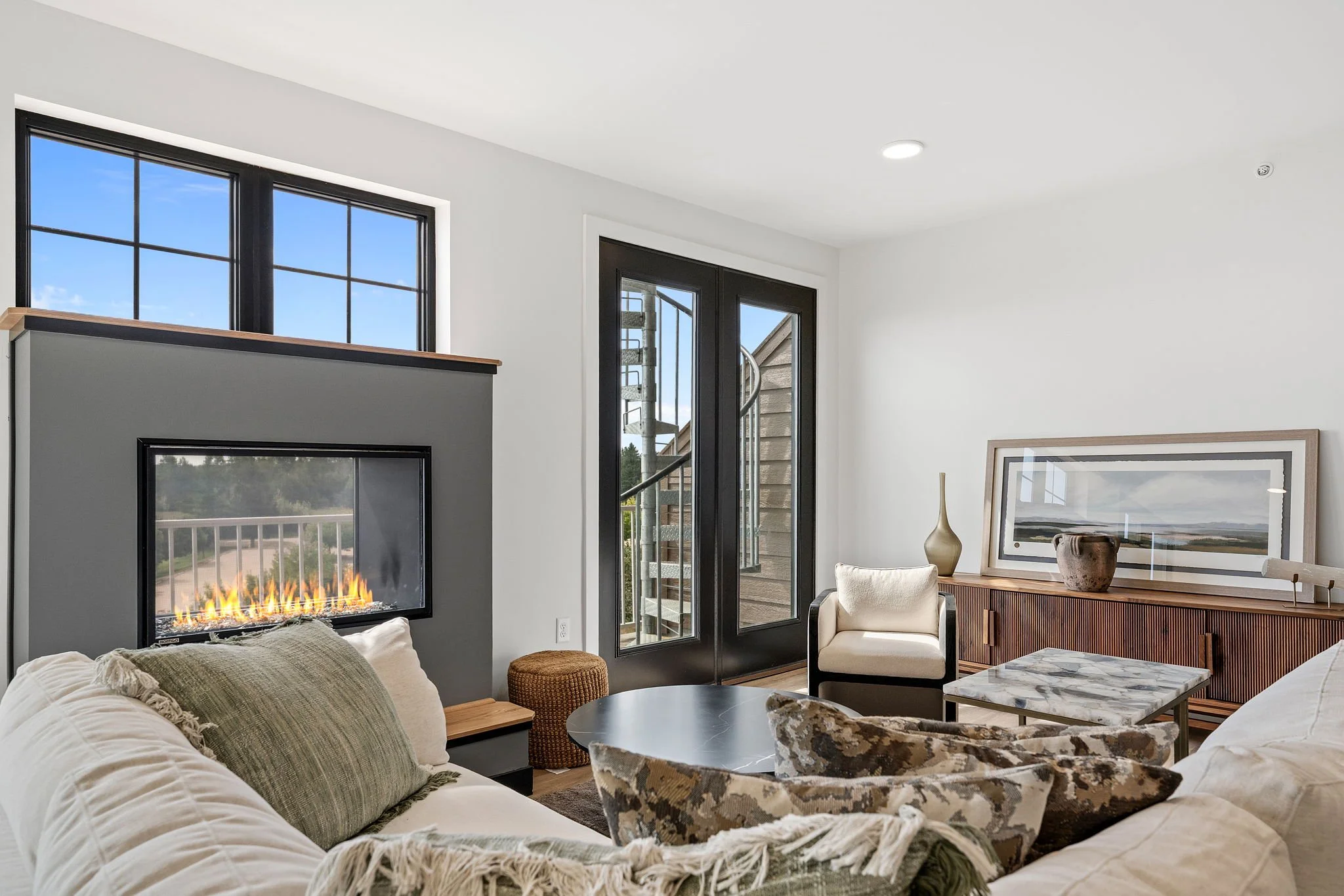 A modern living room with a white sofa, green pillows, and a patterned armchair. The Residences at North Harbor on Lake Superior in Marquette Michigan.