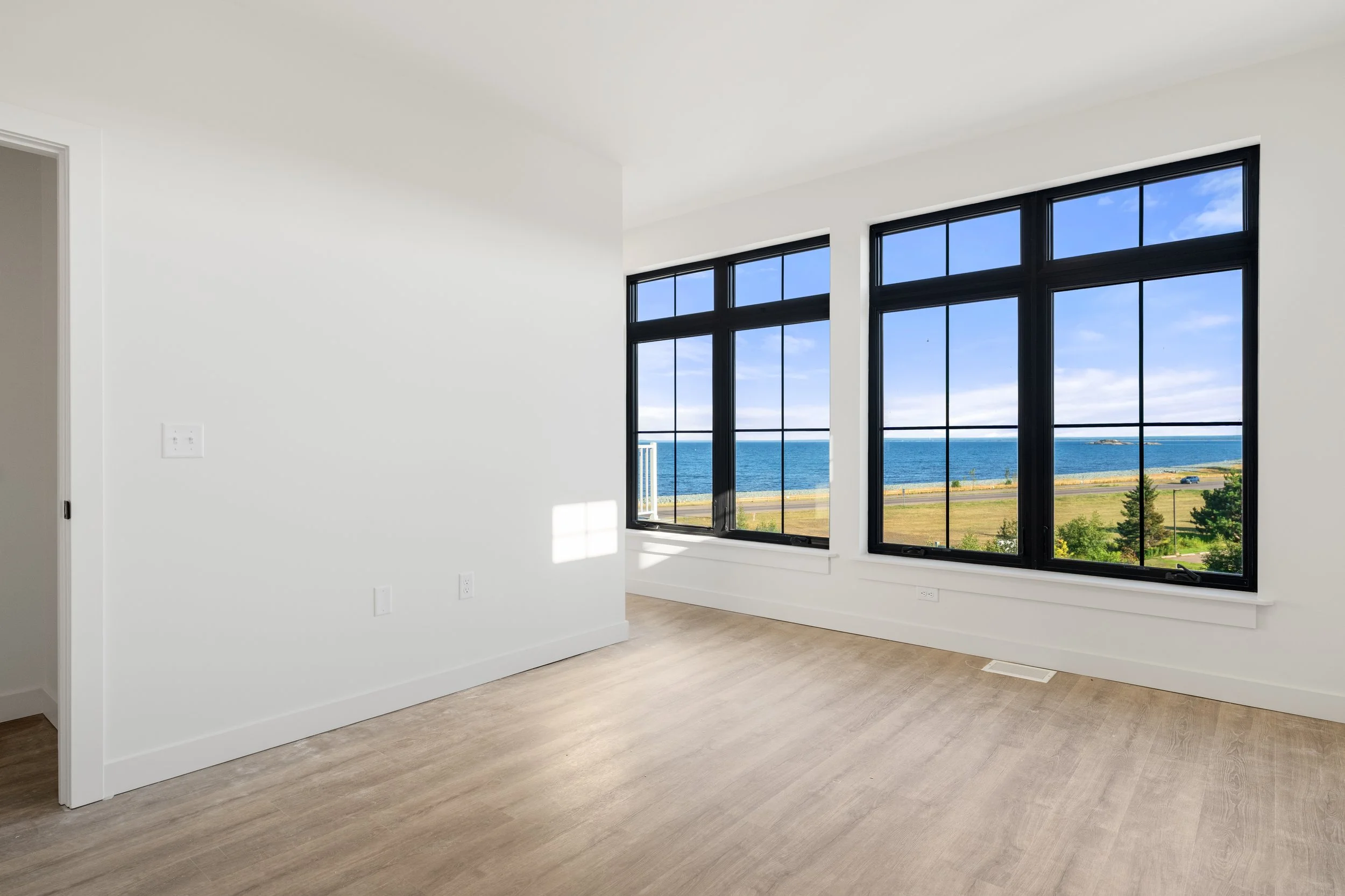 Empty room with large windows showing a view of the ocean and sky. The Residences at North Harbor on Lake Superior in Marquette Michigan.
