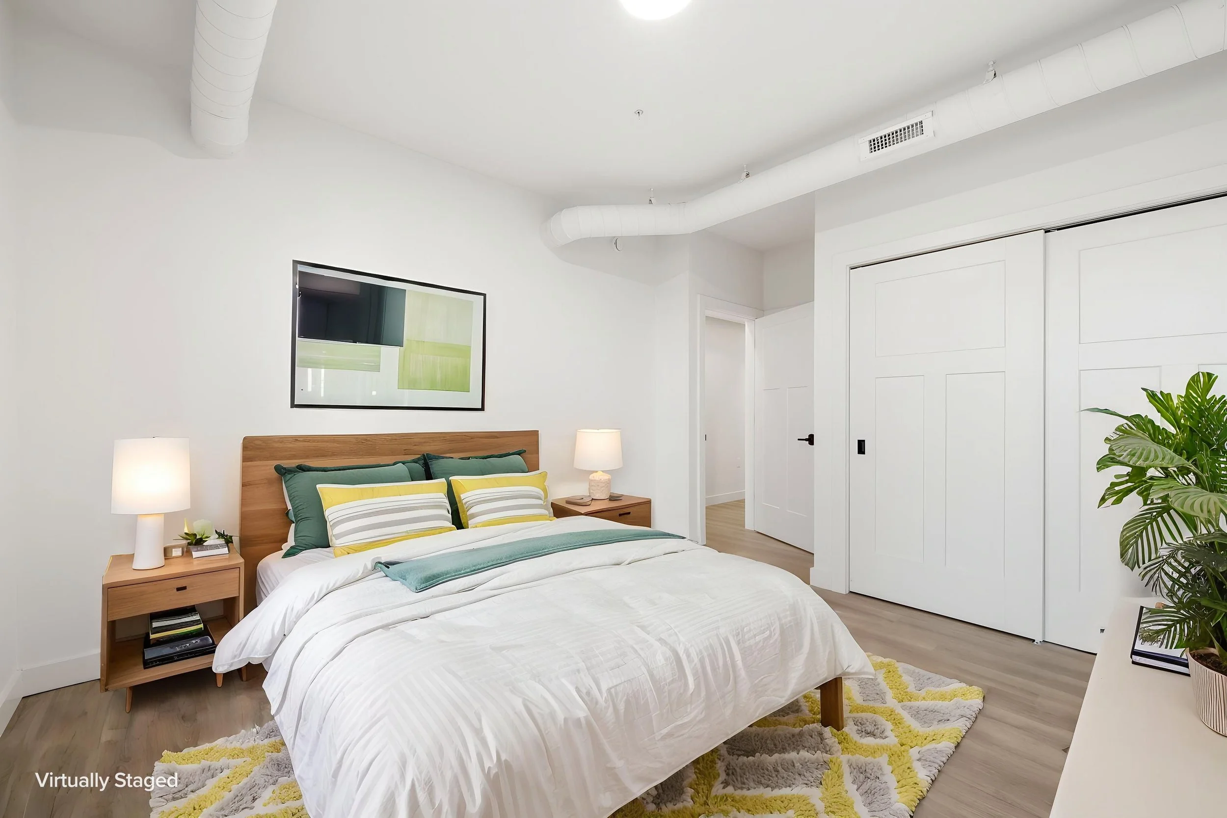 A modern bedroom with a wooden bed frame, white bedding, and green accent pillows. The Residences at North Harbor on Lake Superior in Marquette Michigan.