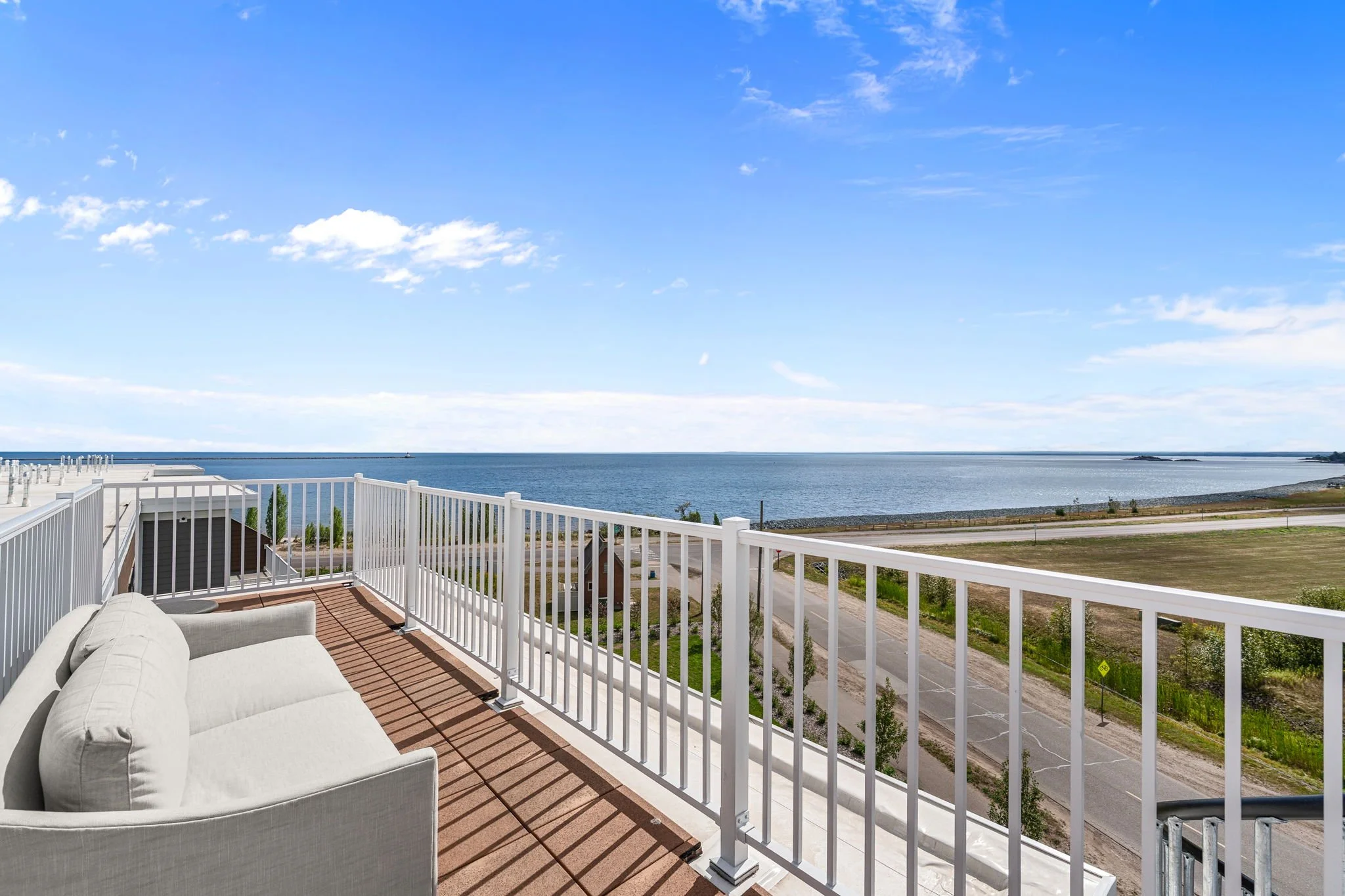 Balcony with white railing overlooking at Lake Superior and a partly cloudy blue sky. The Residences at North Harbor on Lake Superior in Marquette Michigan. 
