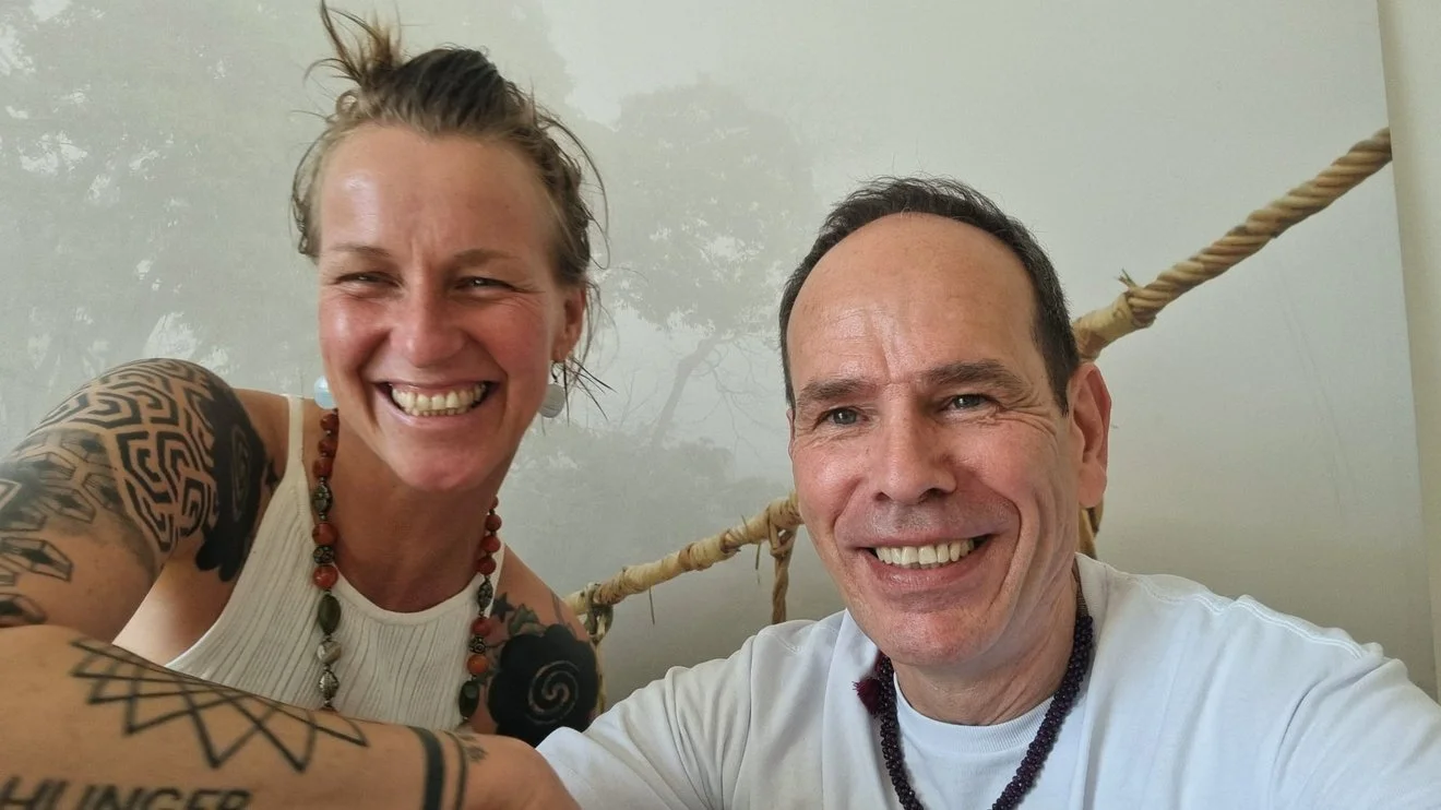 A woman and a man smiling and taking a selfie in front of a foggy background with a rope behind them.