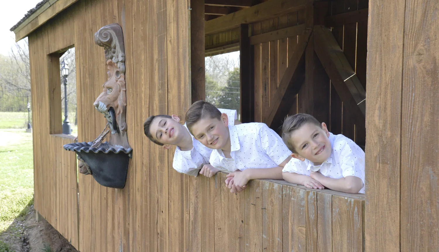 Three brothers leaning through a wooden window