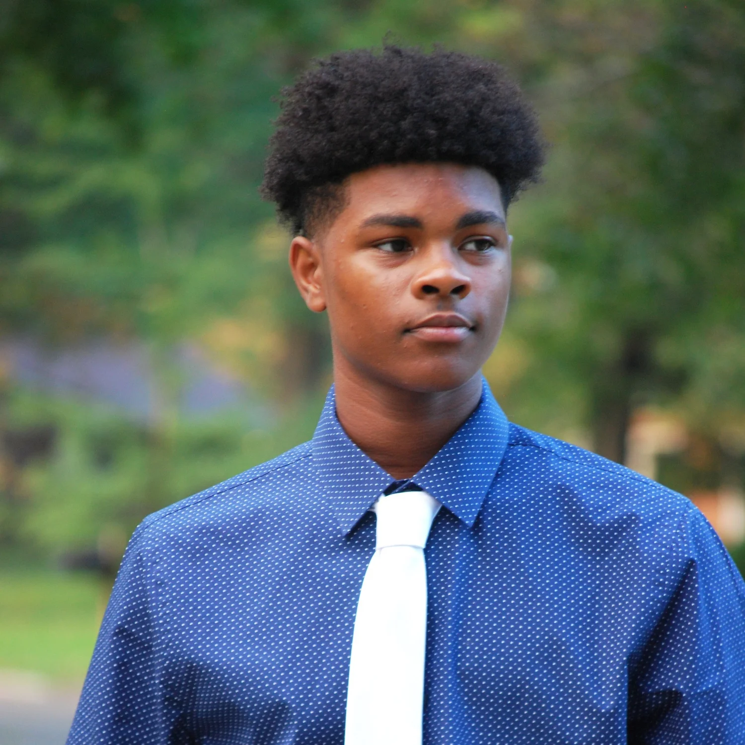 Outdoor portrait of a young man wearing a blue shirt and white tie