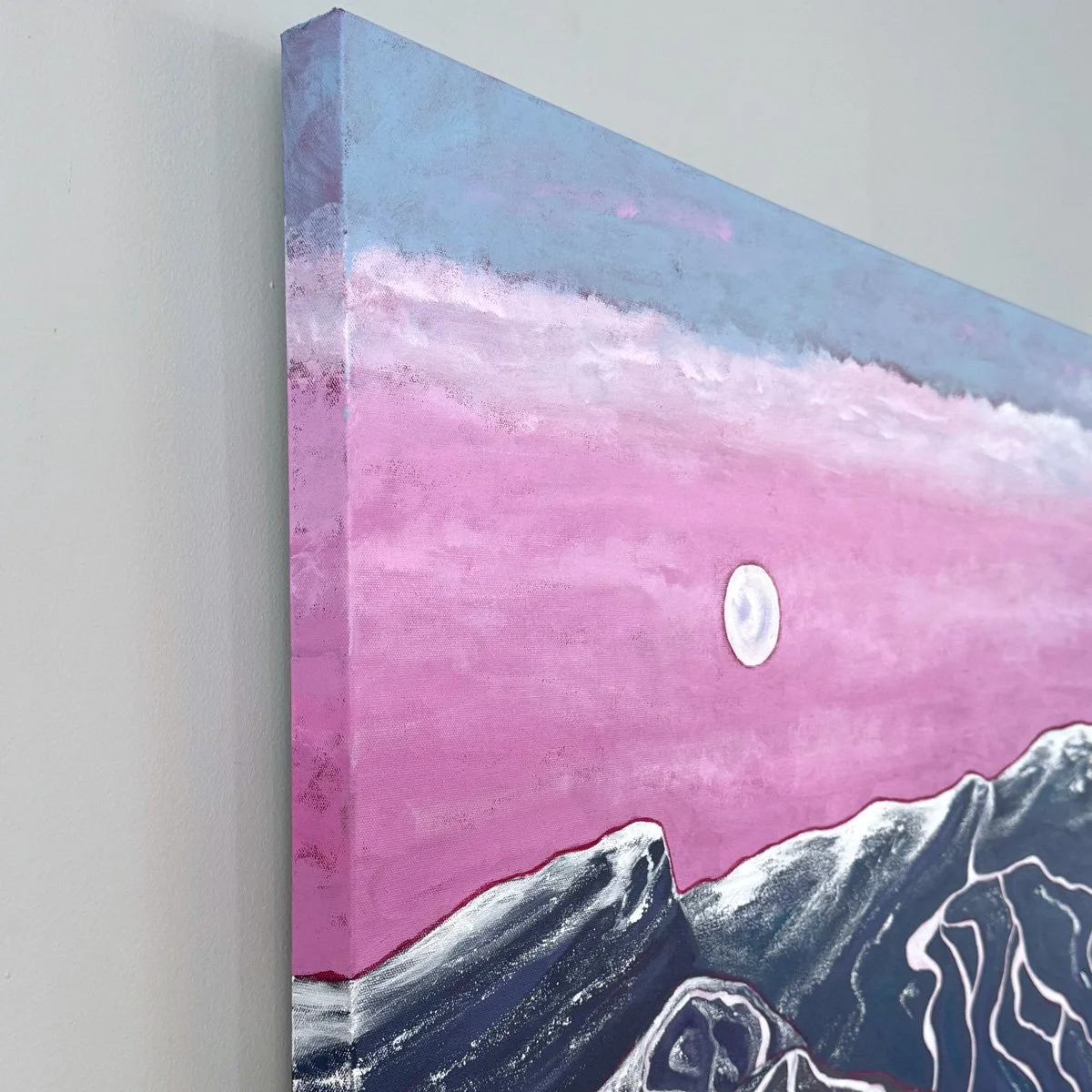 A side view showing the pinks skies and full moon setting behind Stowe mountain. The painting continues around the edges of the canvas.