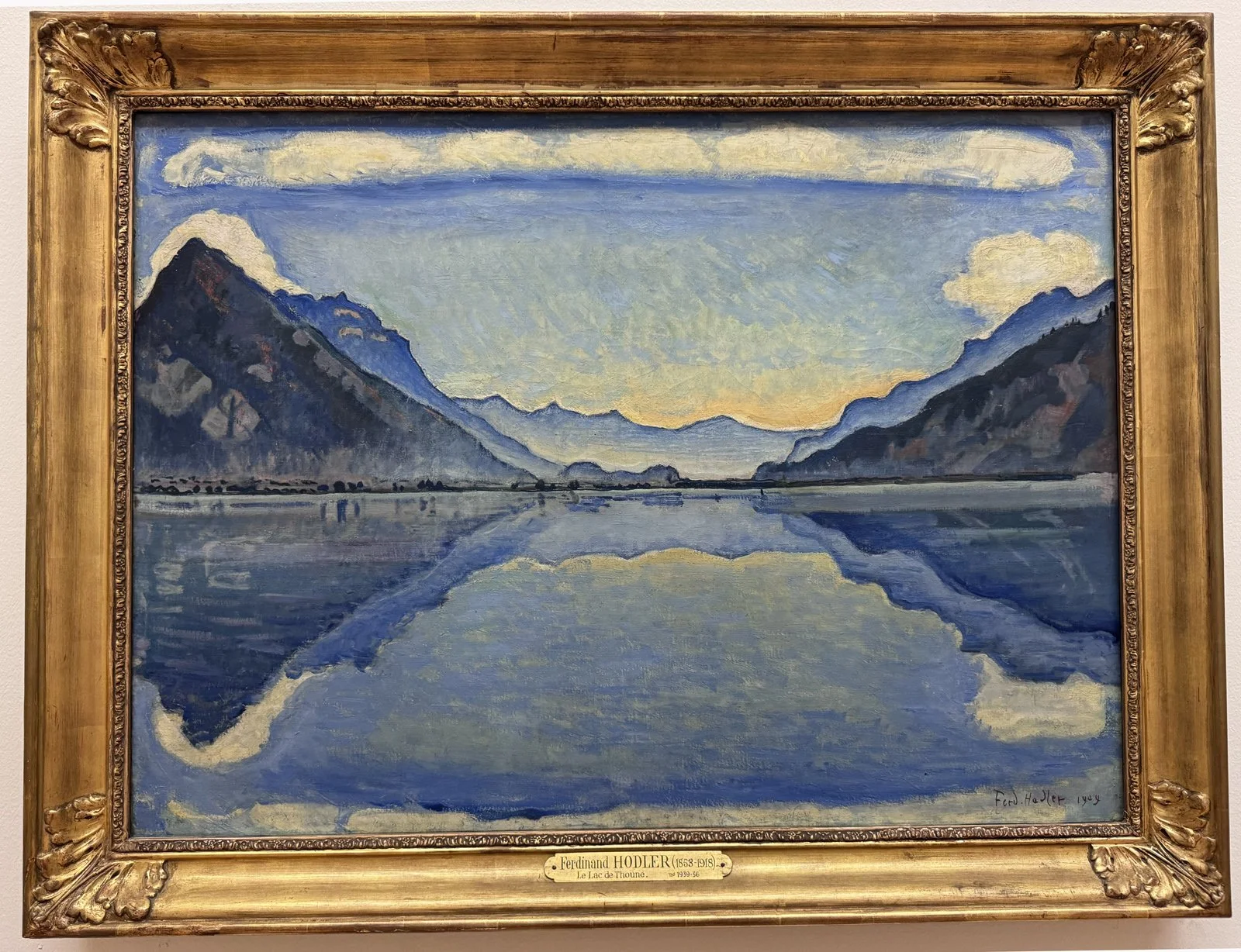 Painting of Lake Thun by Swiss artist Hodler . Blue mountain range is reflected symmetrically in the calm surface of the lake. Soothing blues predominate. Everything is in perfect balance.