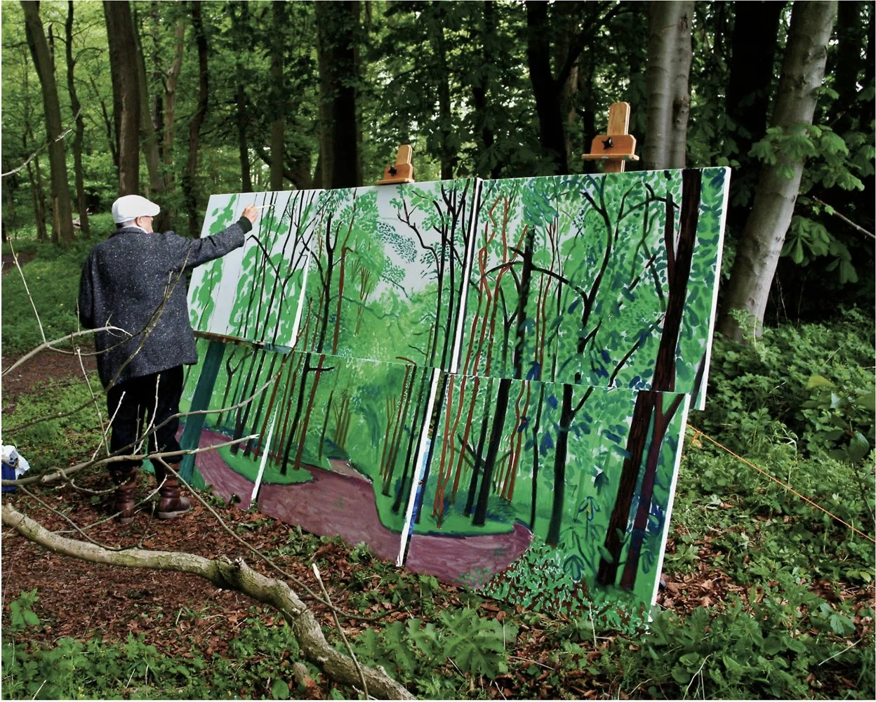 Hockney painting a large-scale painting outdoors, across six panels and three easels. He's paintin in verdant wooods, and green is the predominant color in this painting.