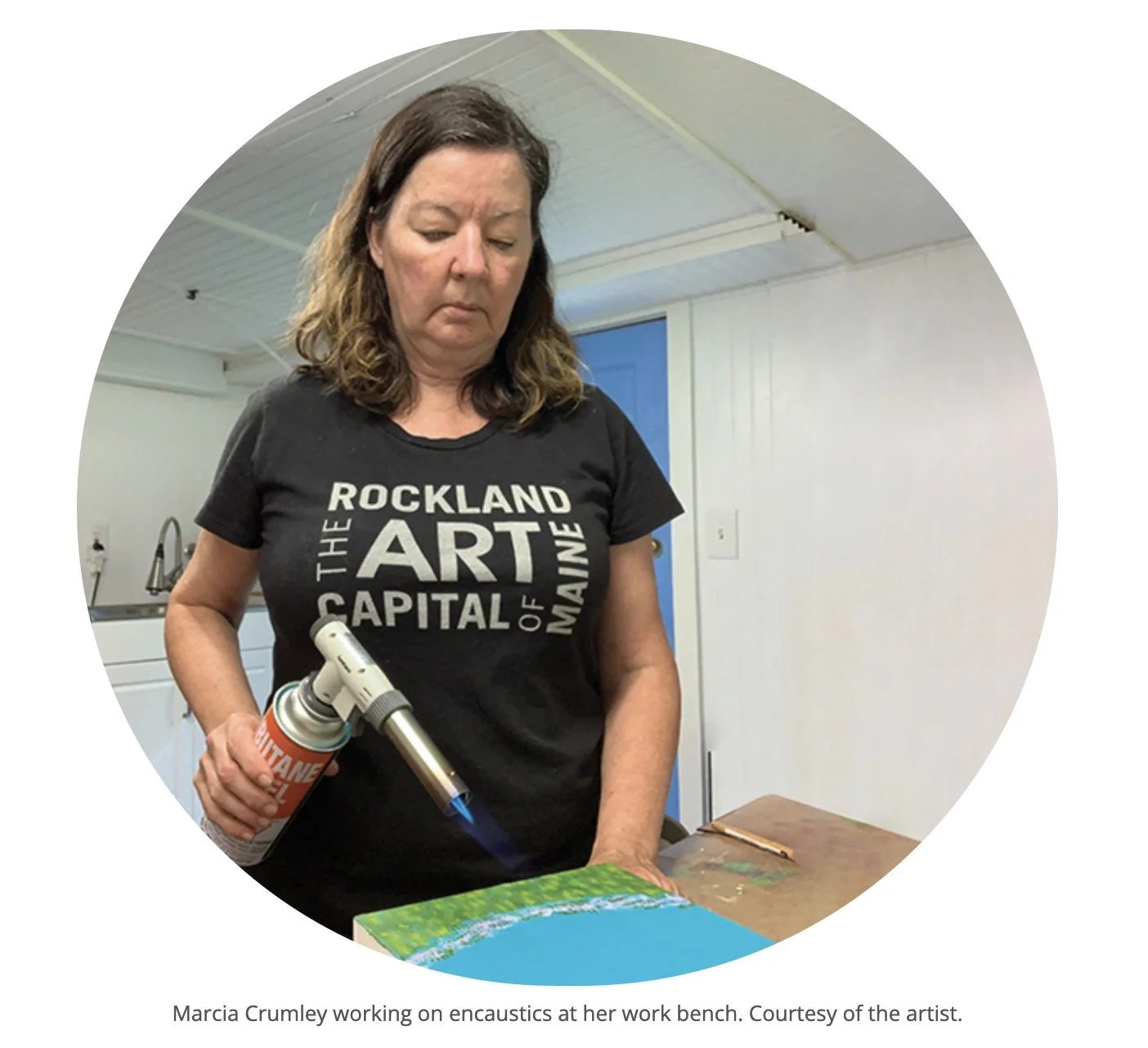 Maine encaustic artist Marcia Crumley using a blowtorch to fuse her encaustic painting.