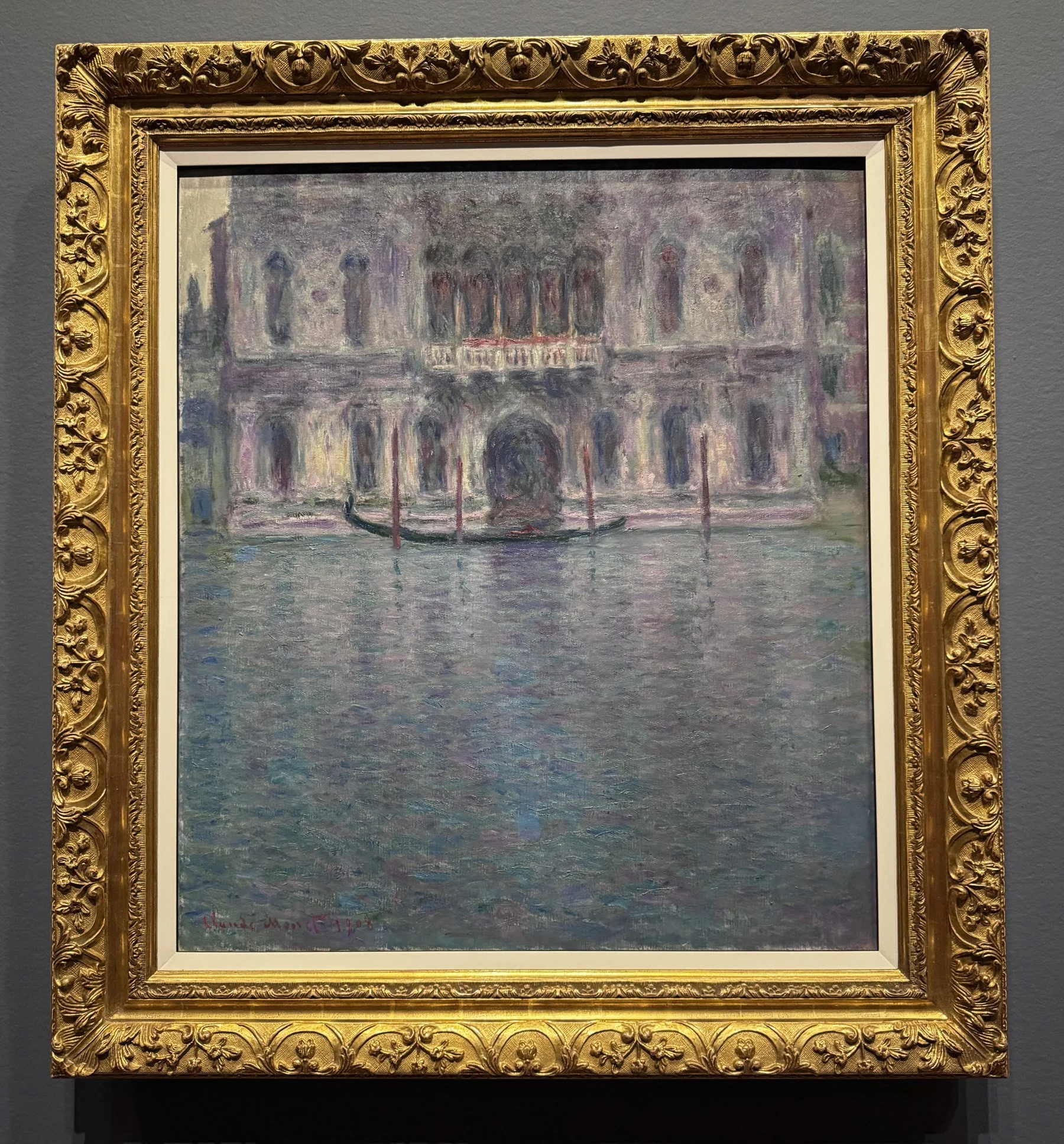 Monet's painting of the facade of the Palazzo Contarini in Venice, with a lone gondola moored in front. Aqua and purple tones predominate.