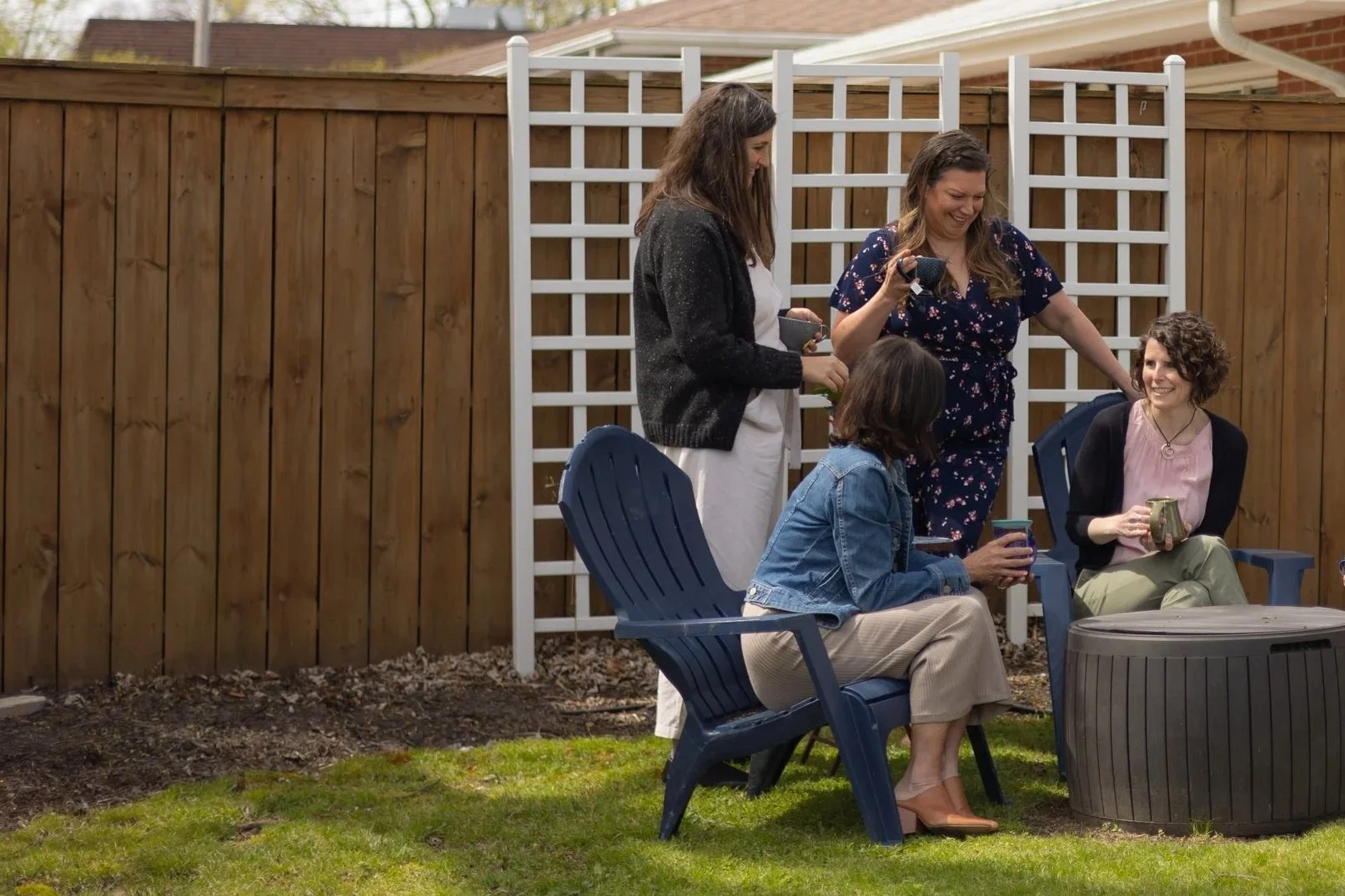 Members of the Empowered Spaces collective sitting and standing holding cups of tea and talking outside.