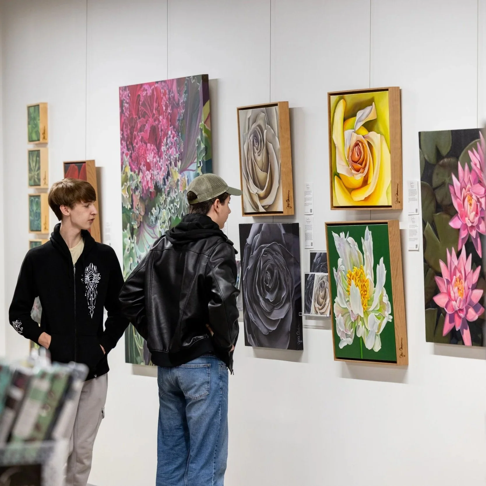 Three people looking at ceramics pieces on pedestal 