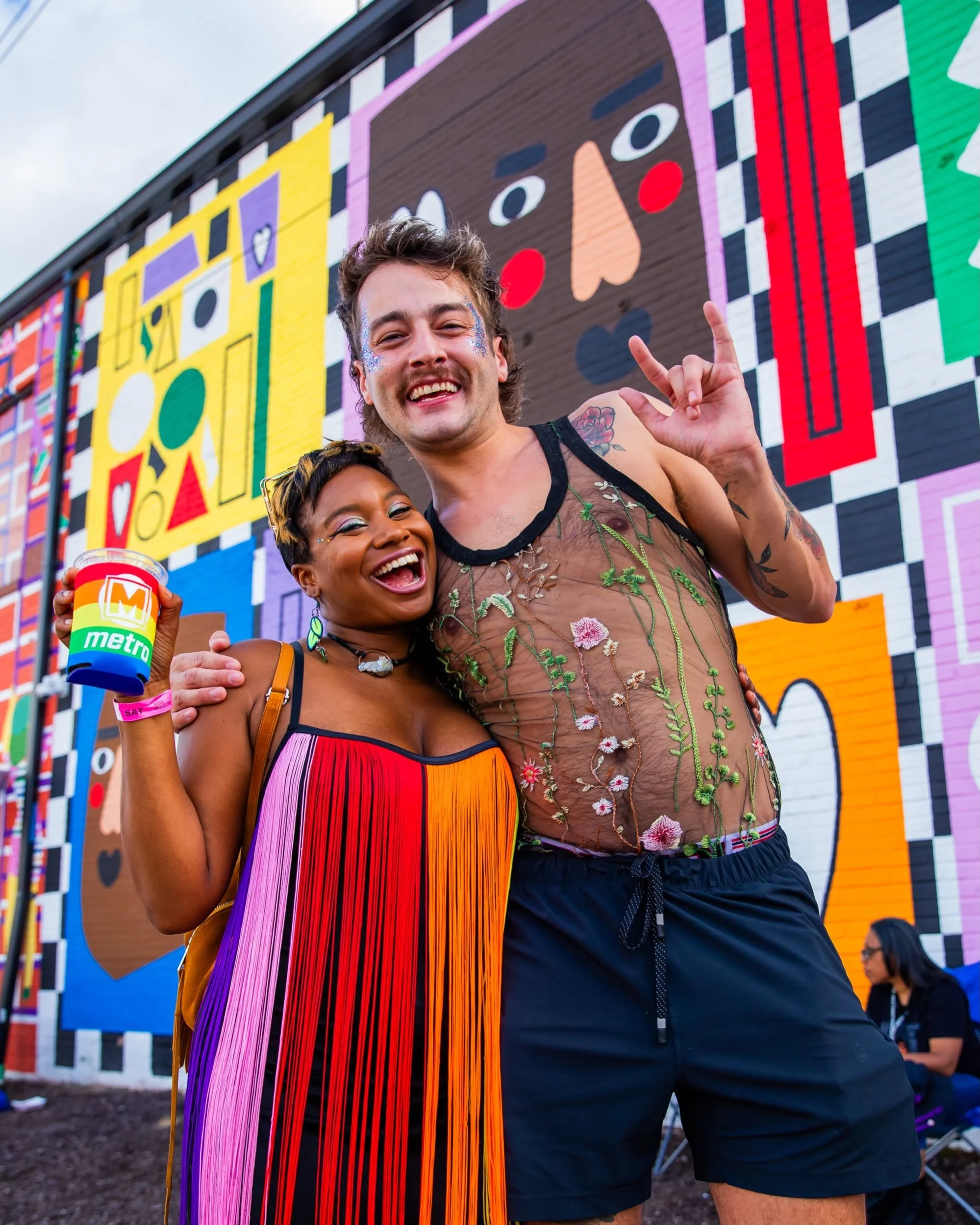Photo of two happy concertgoers standing in front of a mural at MATI Music at the Intersection near The Fountain on Locust