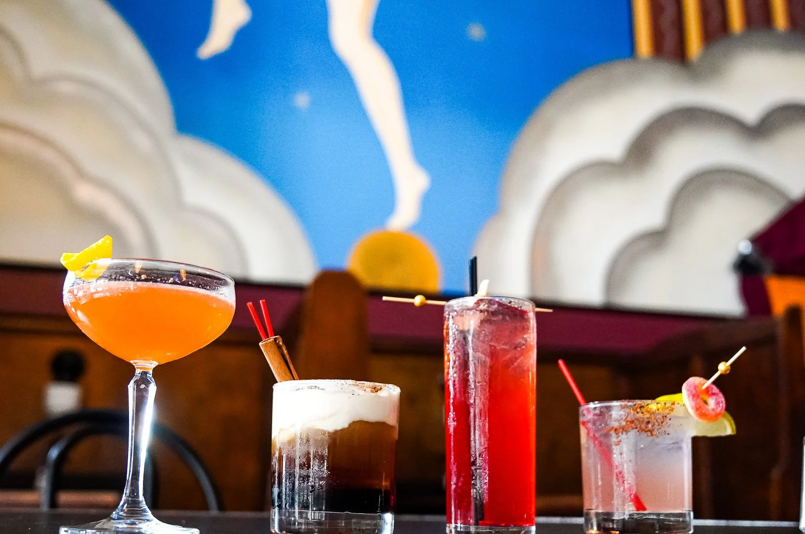 Photo of cocktails sitting on a table at The Fountain on locust. Mural in background.