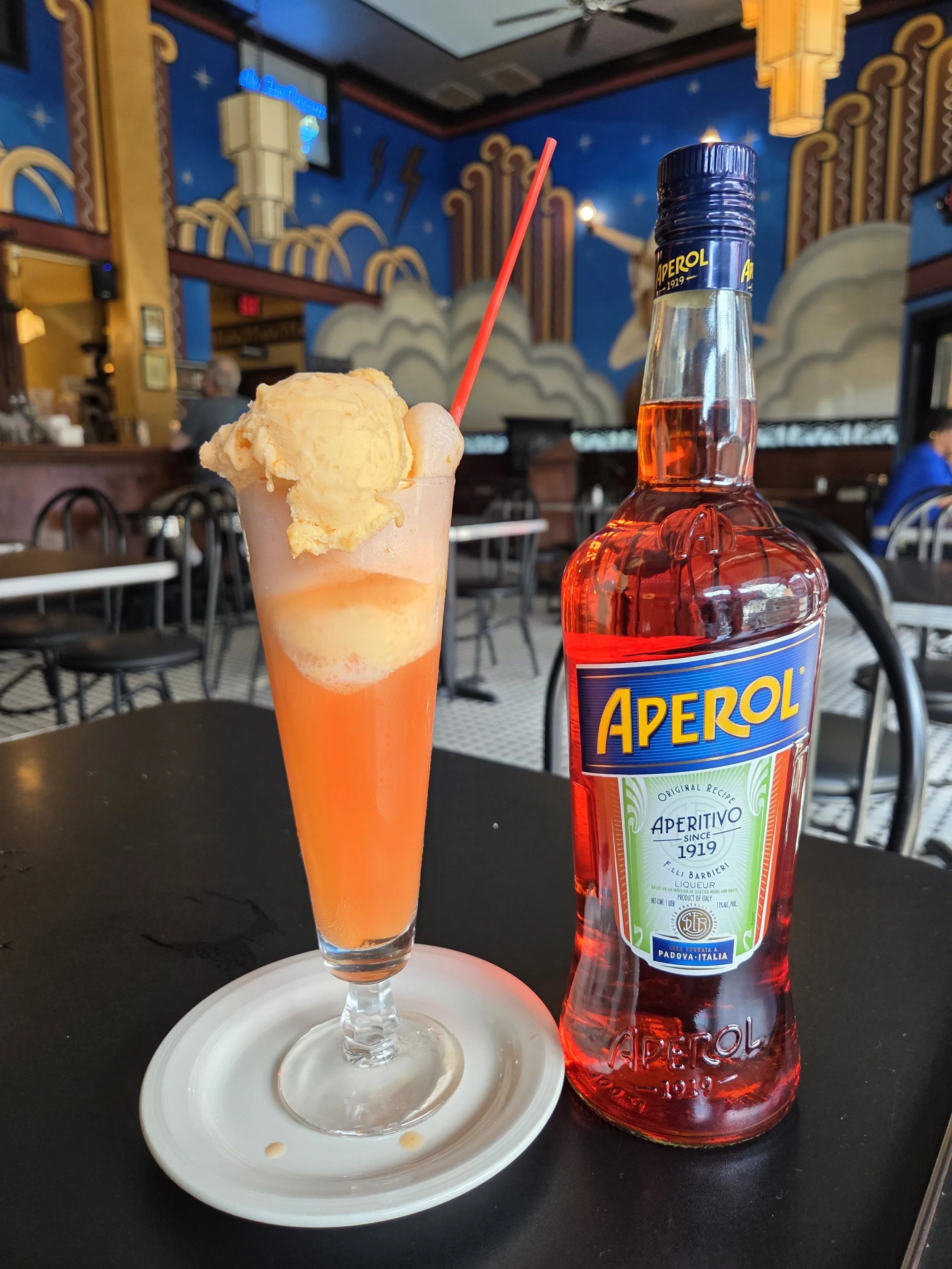 A glass filled with ice cream and aperol sits next to a bottle of Aperol in the dining room at The Fountain on Locust.