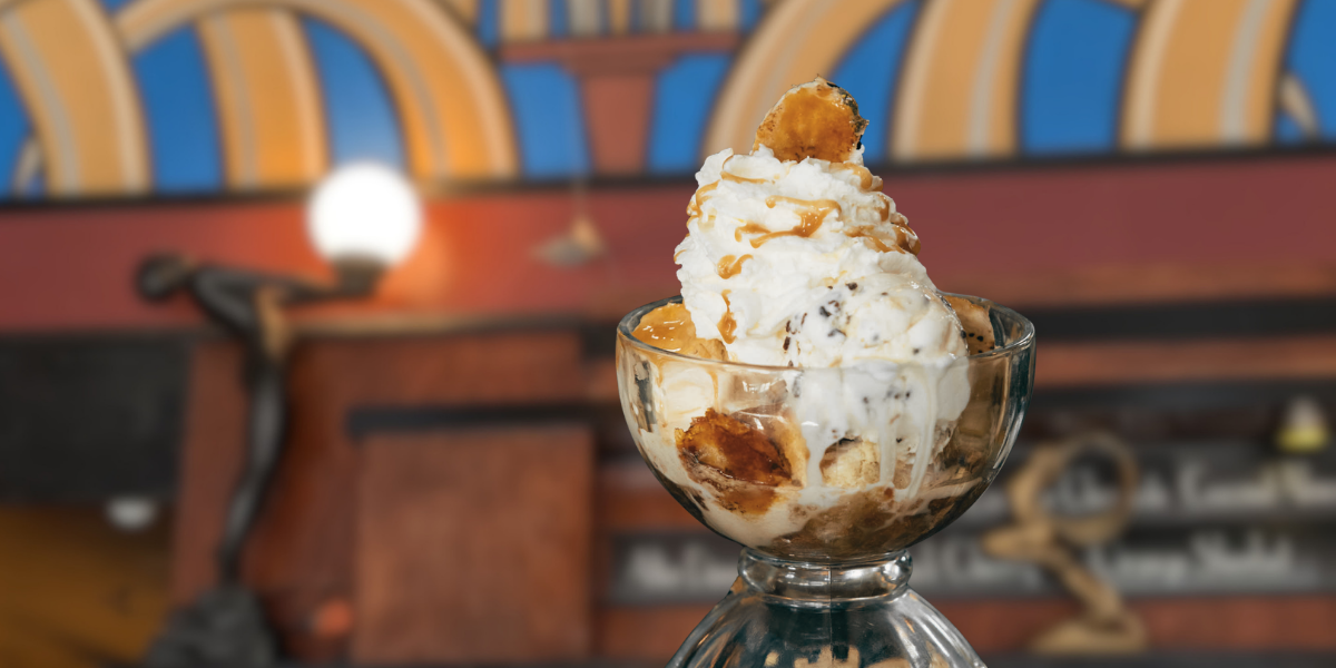 a large crystal bowl of bourbon banana sits on the counter with art deco decor behind it