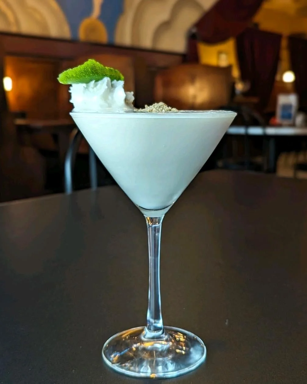 The Key Lime Margarita sits on a table topped with whipped cream and line.