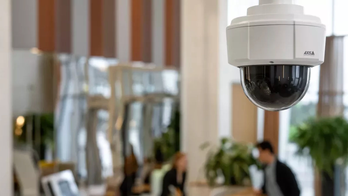 Surveillance. Security camera in an indoor setting with people and furniture in the background.