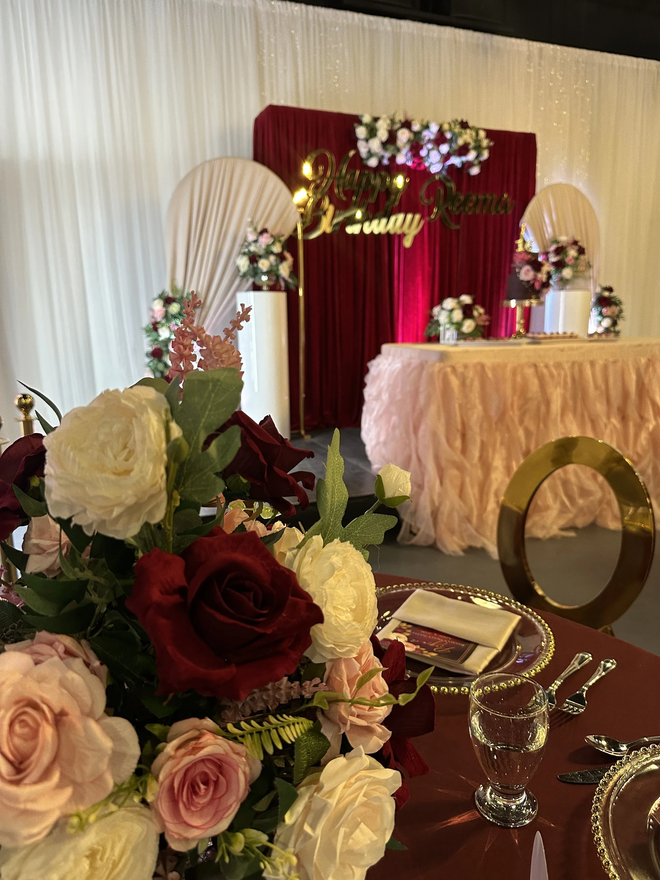 Decorated banquet table with flowers, wine glasses, and elegant tableware, set for a celebration or event with a festive background.