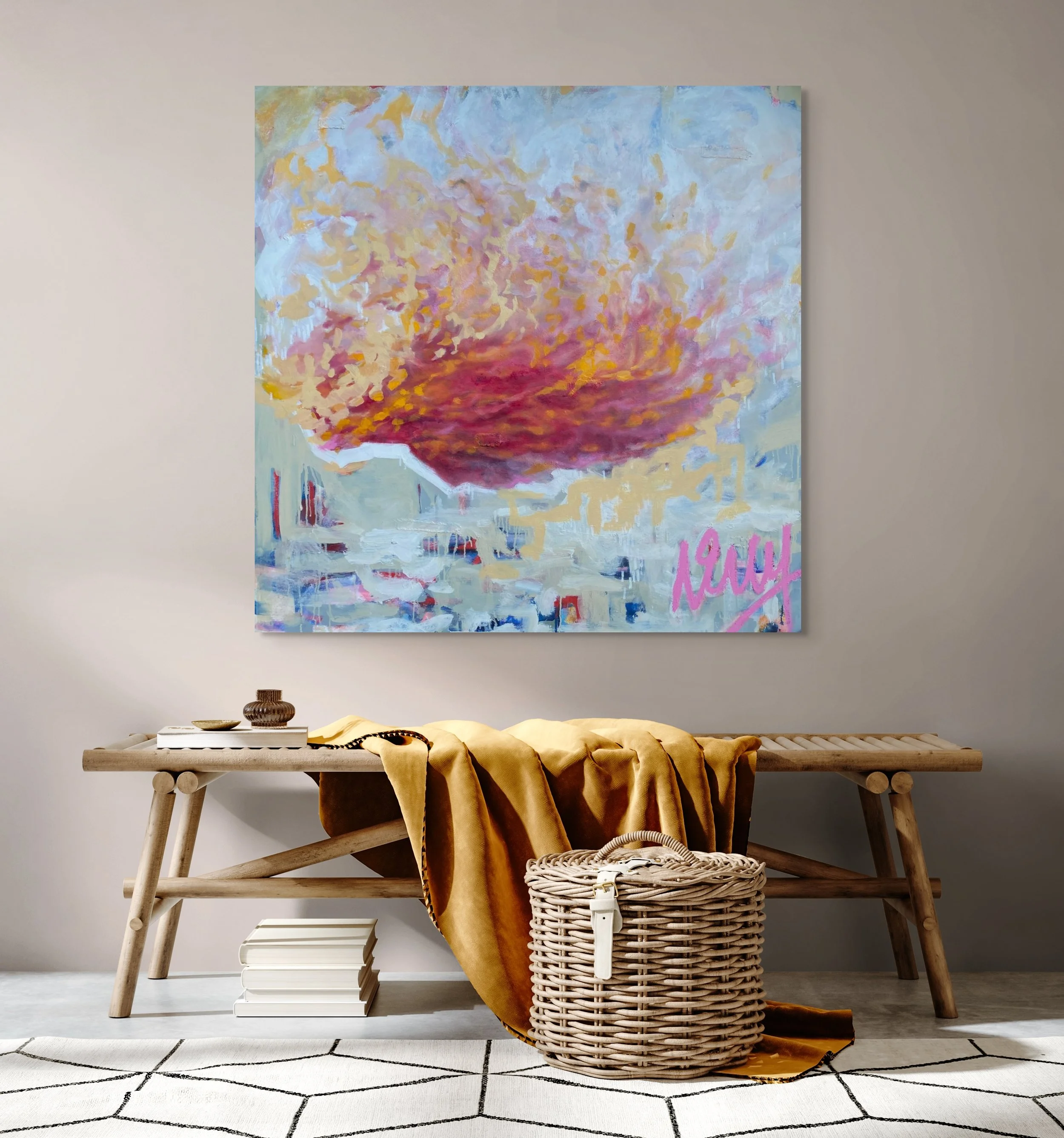 Abstract colorful painting on a wall above a simple wooden bench with a yellow draped fabric, basket, and books in a minimalistic room.