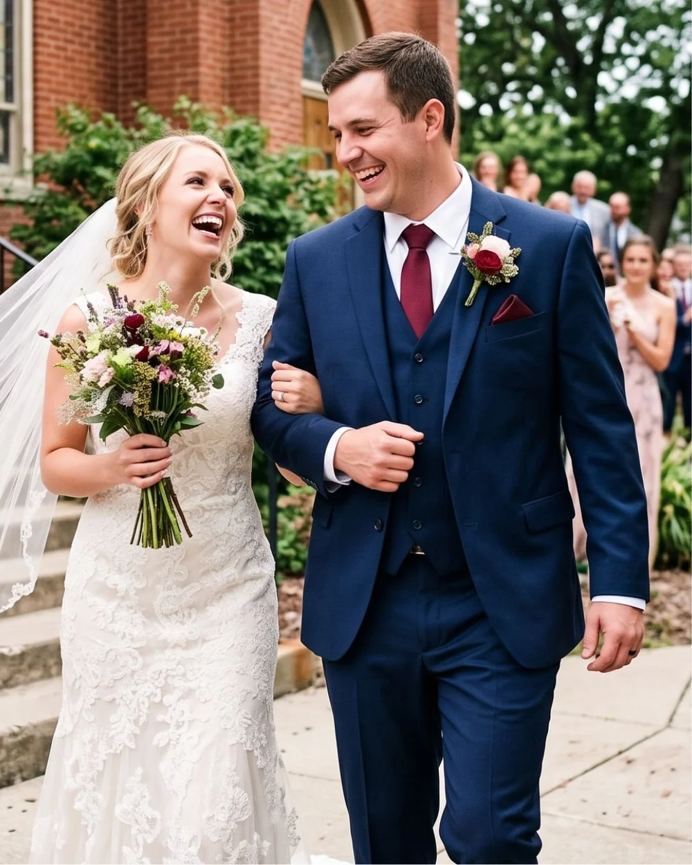 Couple walking arm in arm after their ceremony, groom in a navy three-piece suit with a burgundy tie