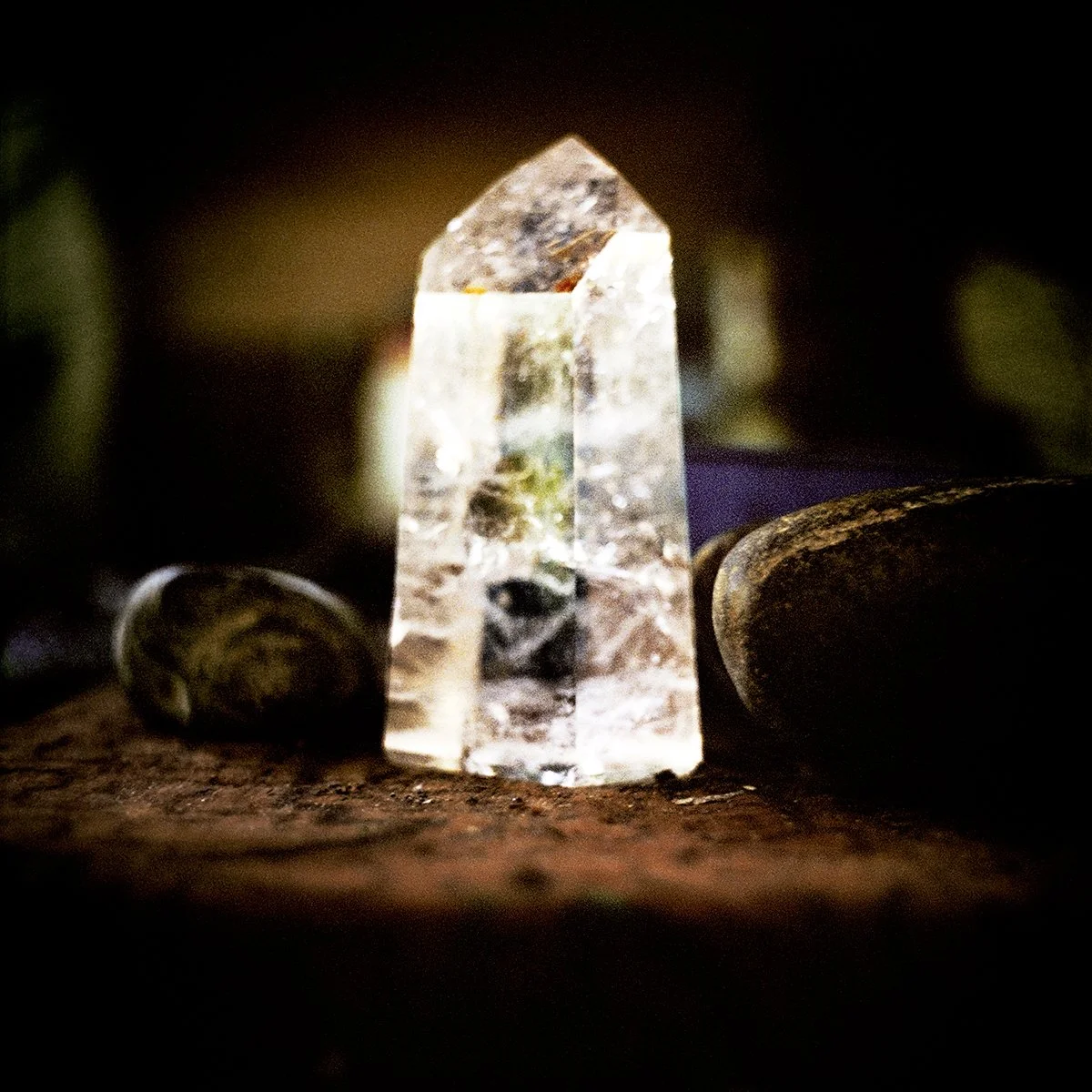 Clear crystal with geometric structure, surrounded by stones, set on a wooden surface.