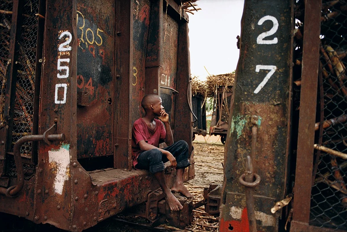 Young boy sitting in a rusty old locomotive in a rural setting