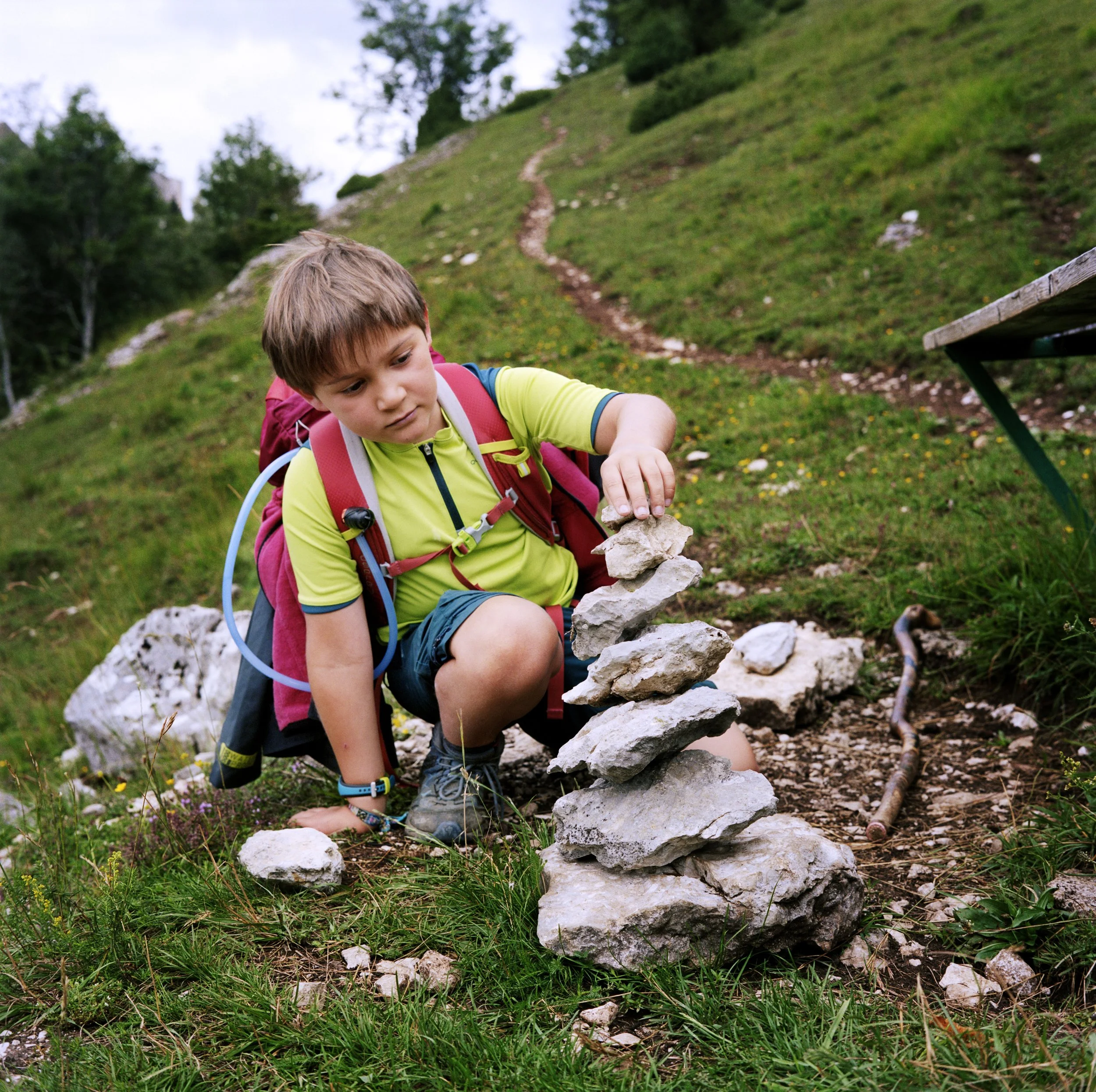 A boy building a stone tower on a nature hike.