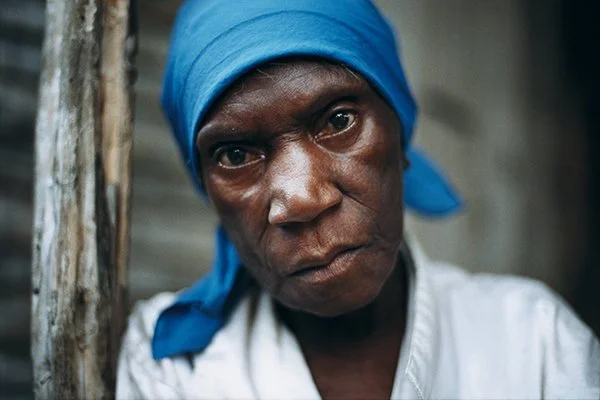 Portrait d'une femme portant un bandana bleu, regardant intensément l'objectif.