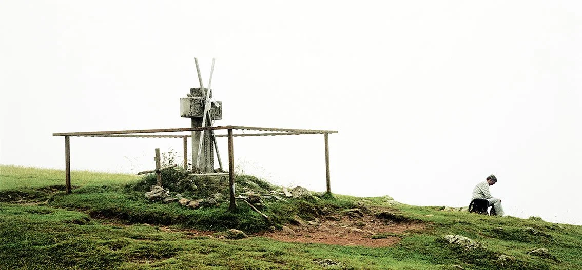 Landscape with an old stone mill and a man sitting on the ground beside it.